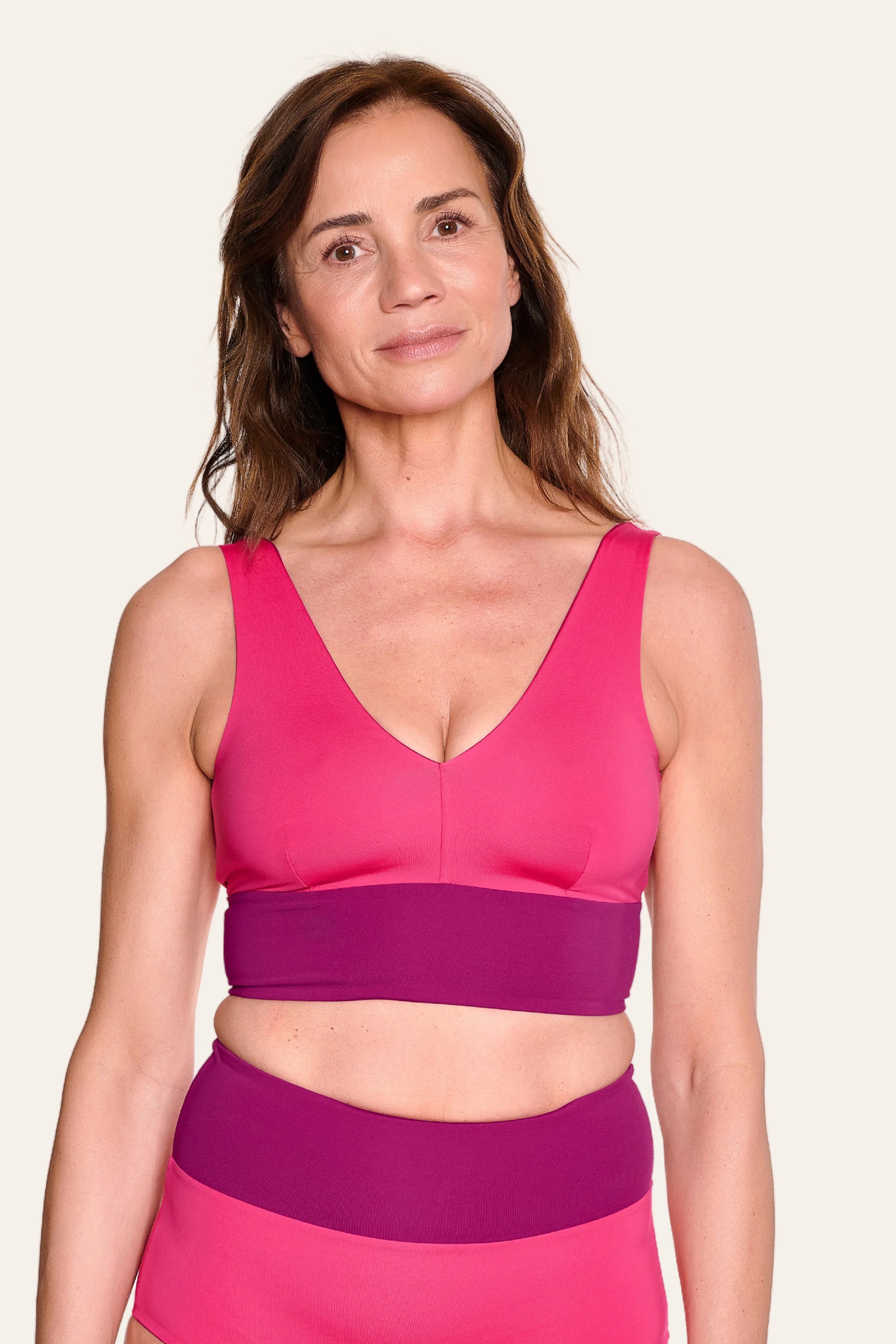 Frau trägt MYMARINI Bikinitop mit V-Ausschnitt und breite Träger in Pink und Lila.#color_pink-hortensia