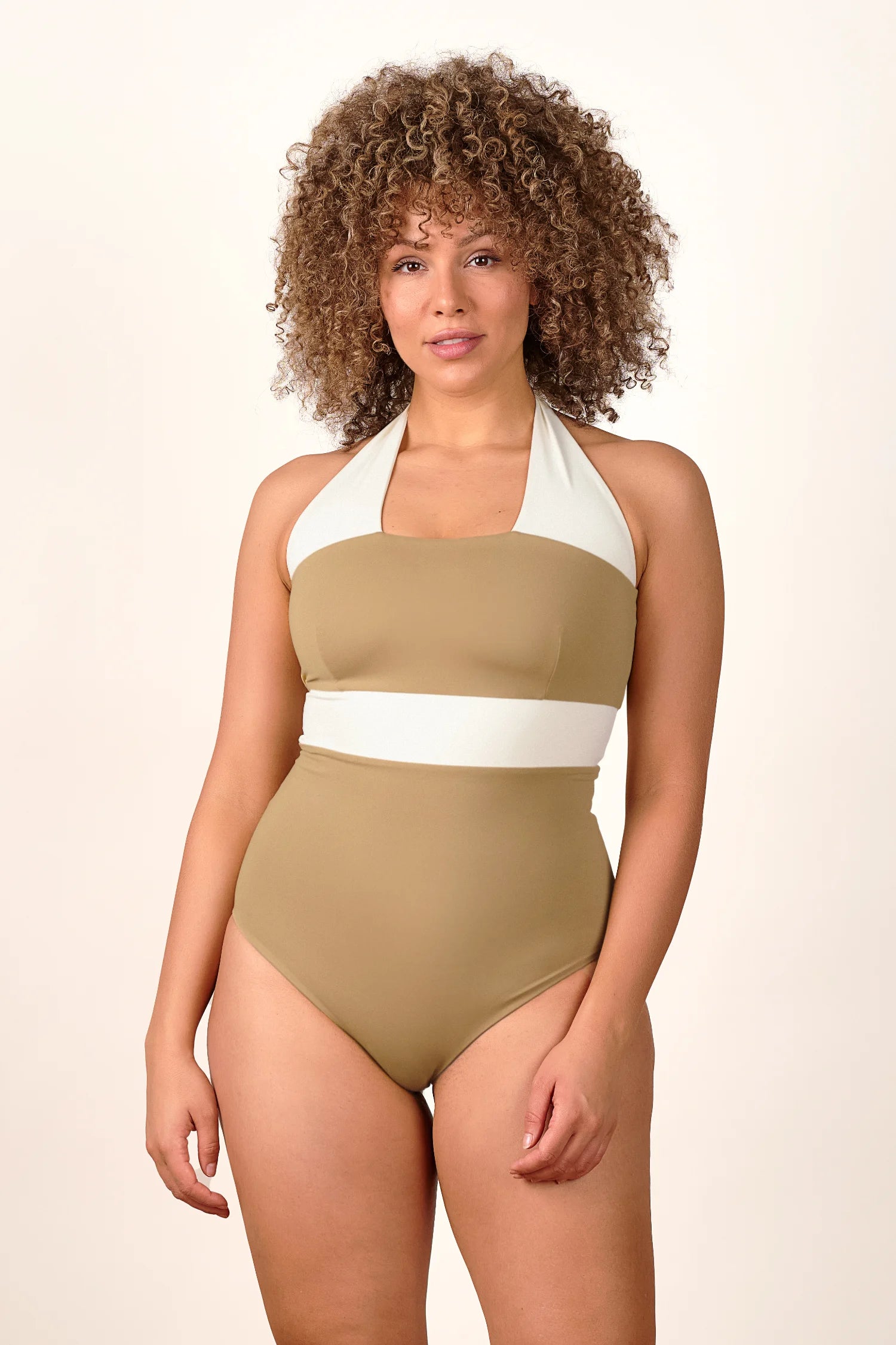 Person trägt einen MYMARINI One-Piece Badeanzug mit Neckholder und hohem Beinausschnitt in Beige und Weiß.#color_coast-desert