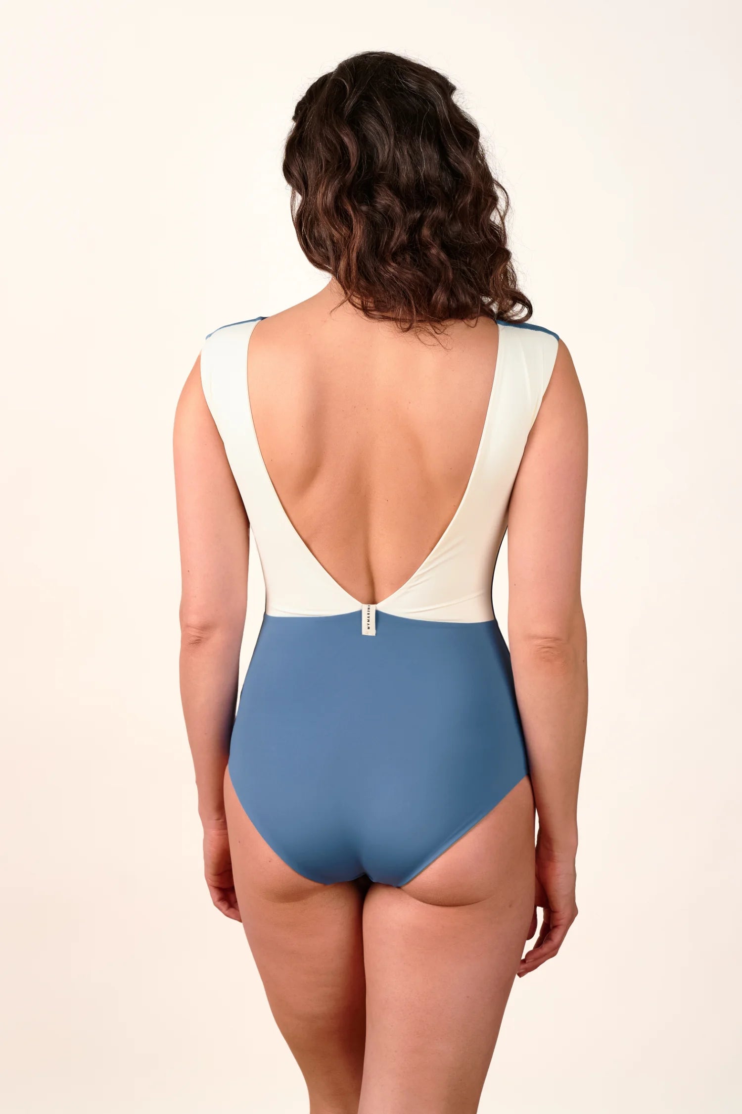 Rückansicht eines MYMARINI Badeanzugs mit tiefem Rückenausschnitt und breiten Trägern in Blau und Weiß.#color_coast-desert