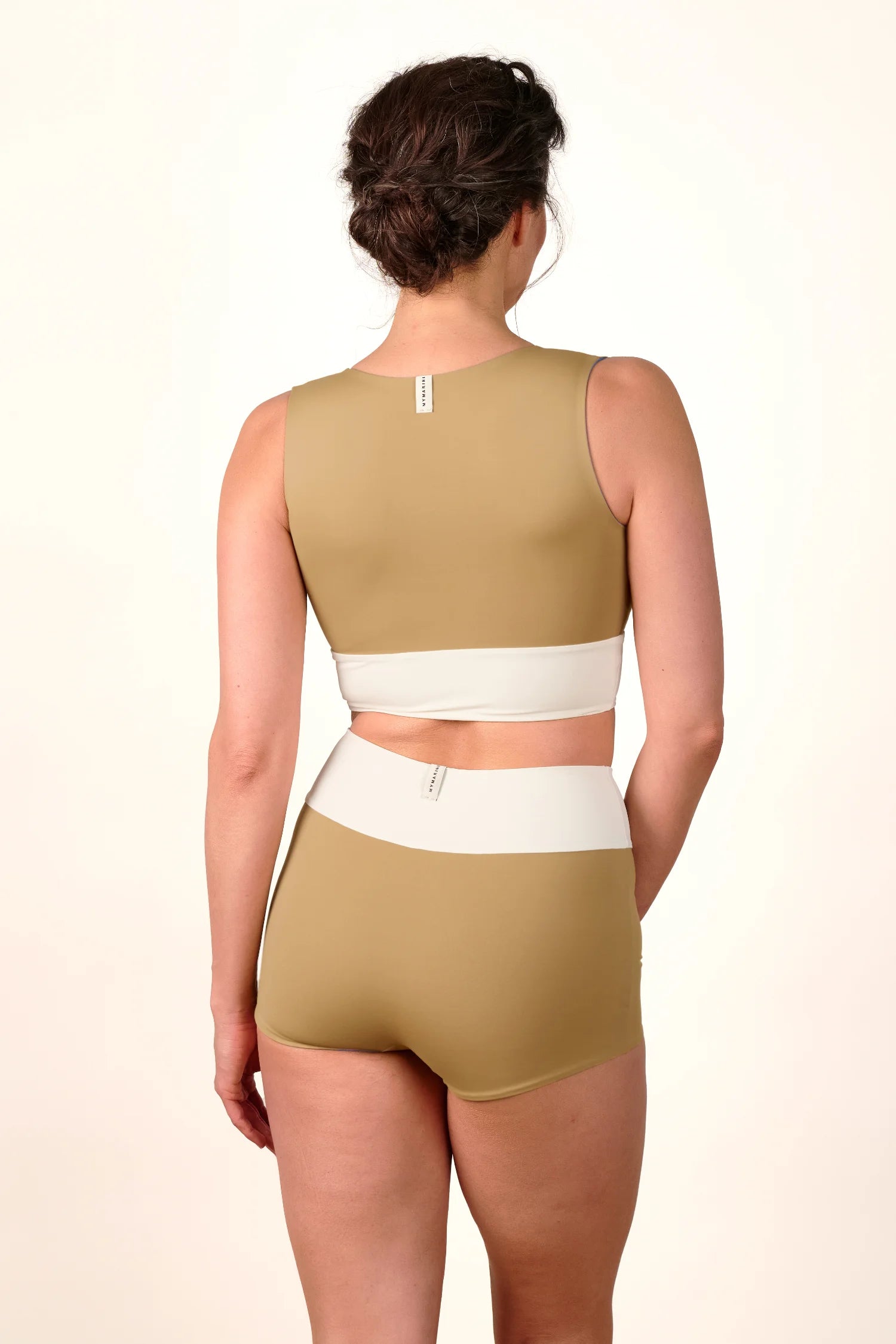 Rückansicht einer Frau in einem MYMARINI Bikini-Set mit breiten Trägern und hohem Beinausschnitt in Beige und Weiß.#color_coast-desert
