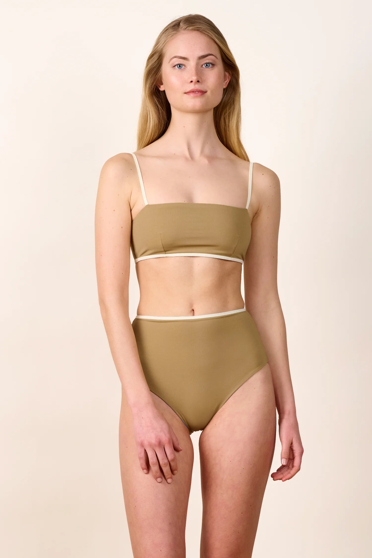 Frau trägt MYMARINI Bikini mit Bandeau-Top und High-Waist-Hose in Beige.#color_coast-desert