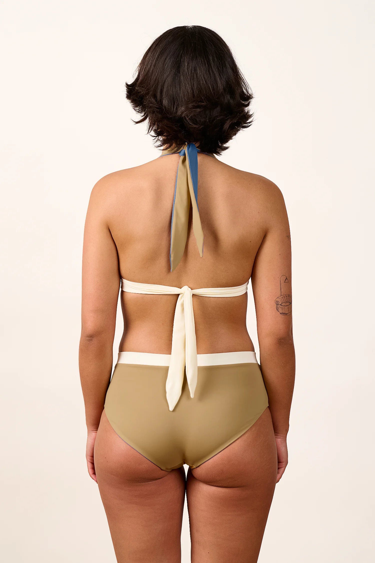 Frau in MYMARINI Bikini mit Neckholder und High Waist Schnitt, Rückansicht.#color_coast-desert