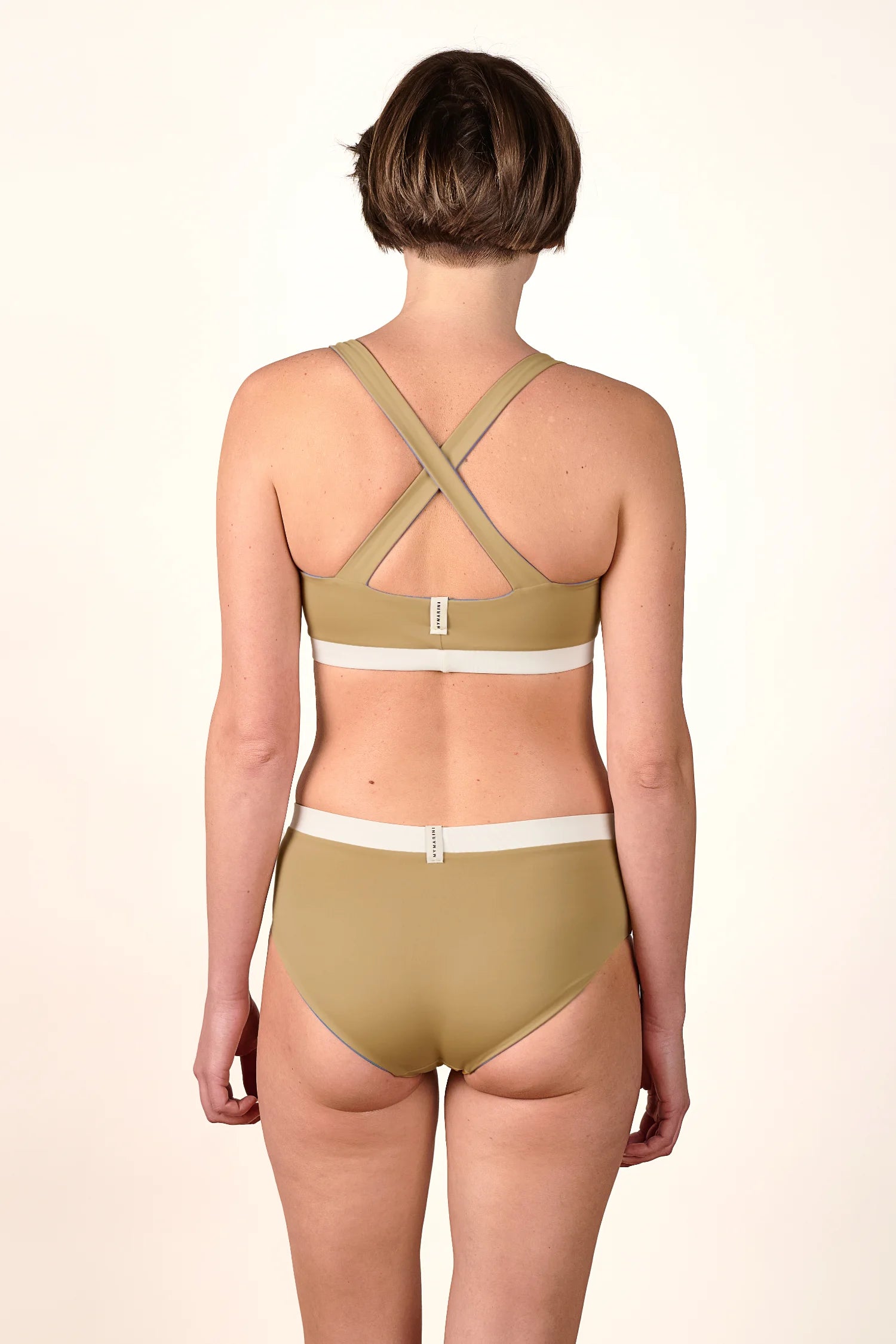 Rückansicht einer Person in MYMARINI Bikinihose und Cross Top mit breiten Trägern, hoch geschlossen, in Beige.#color_coast-desert