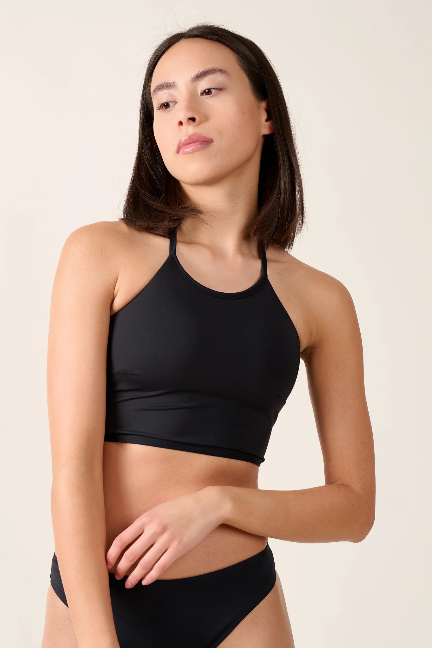 Frau trägt MYMARINI Bikinitop mit hohem Ausschnitt und schmalen Trägern in Schwarz.#color_black-navy