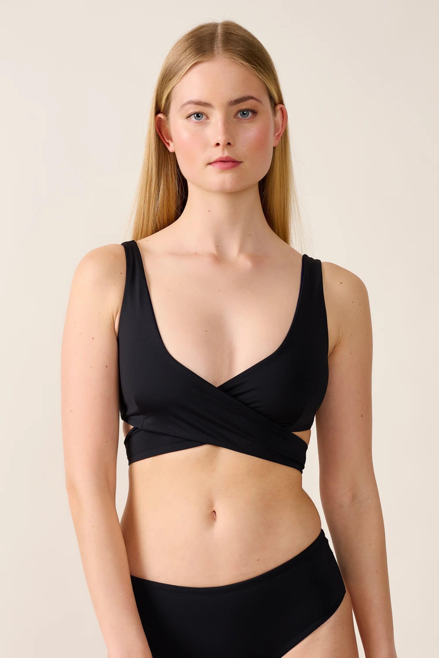 Frau trägt MYMARINI Bikinitop mit V-Ausschnitt und breiten Trägern in Schwarz.#color_black-navy