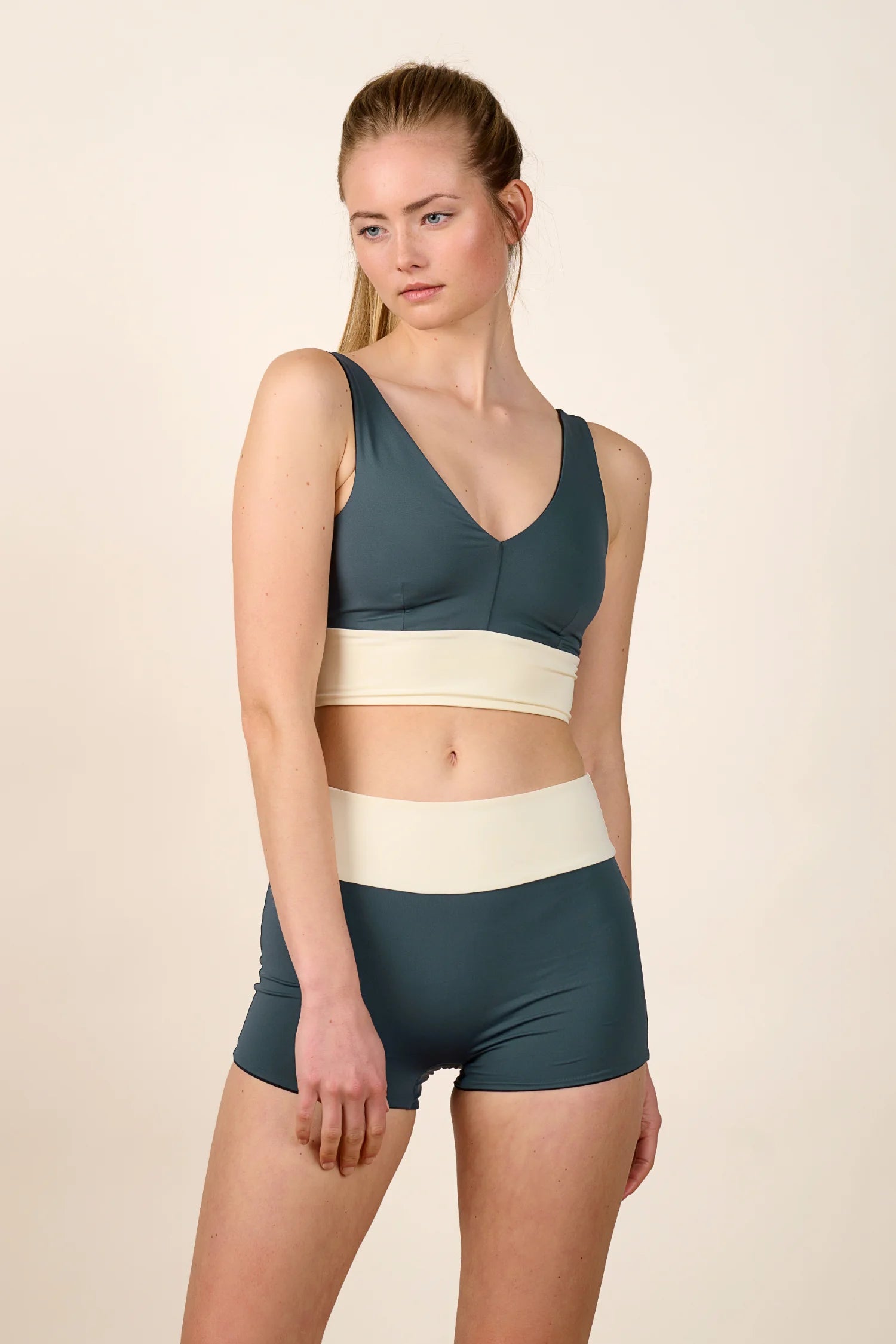 Frau trägt MYMARINI Bikinitop mit V-Ausschnitt und Bikinihose mit High Waist in Blau und Creme.#color_black-grey-white