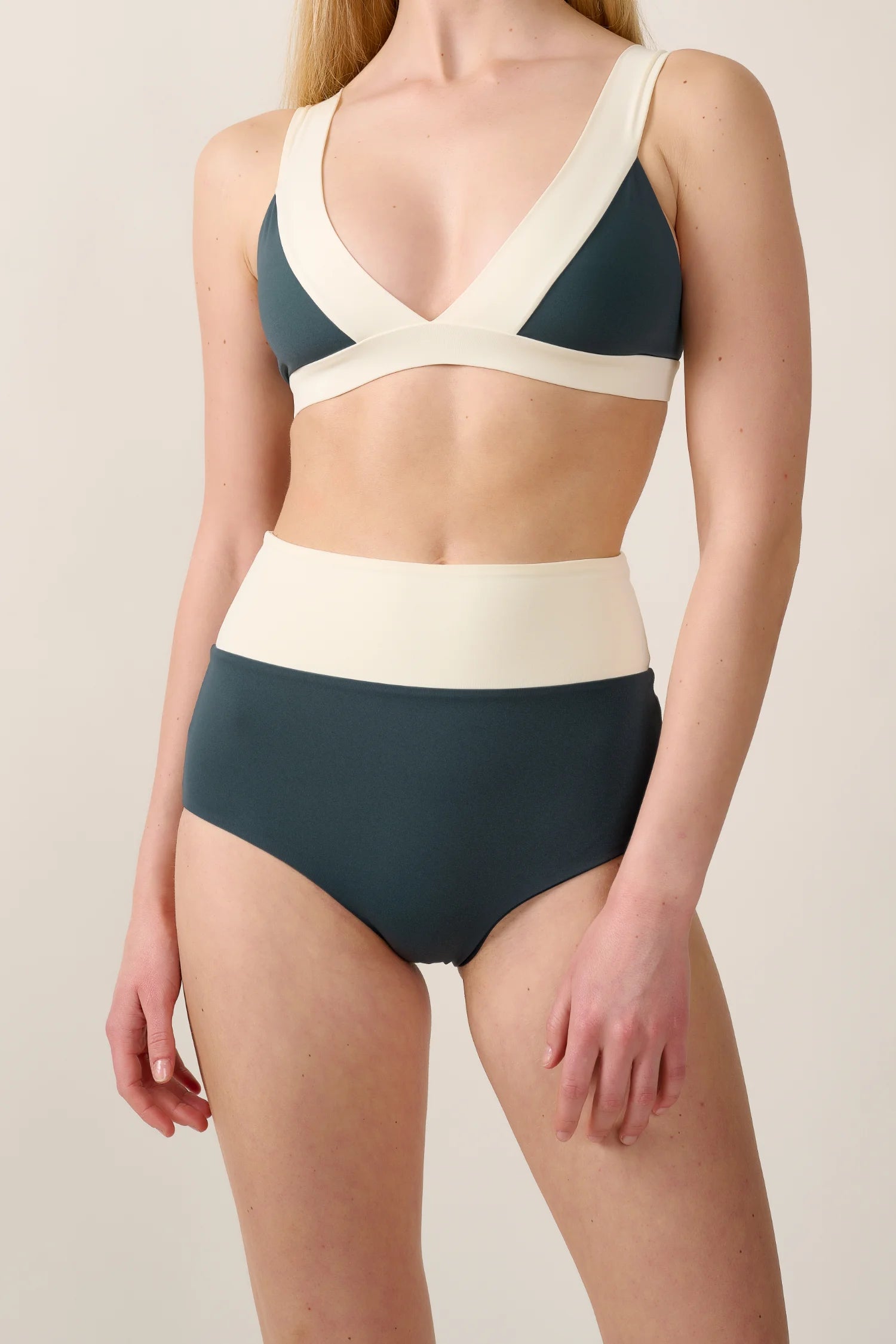 Frau trägt MYMARINI Bikini mit V-Ausschnitt und High Waist Schnitt in Dunkelgrün und Creme.#color_black-grey-white
