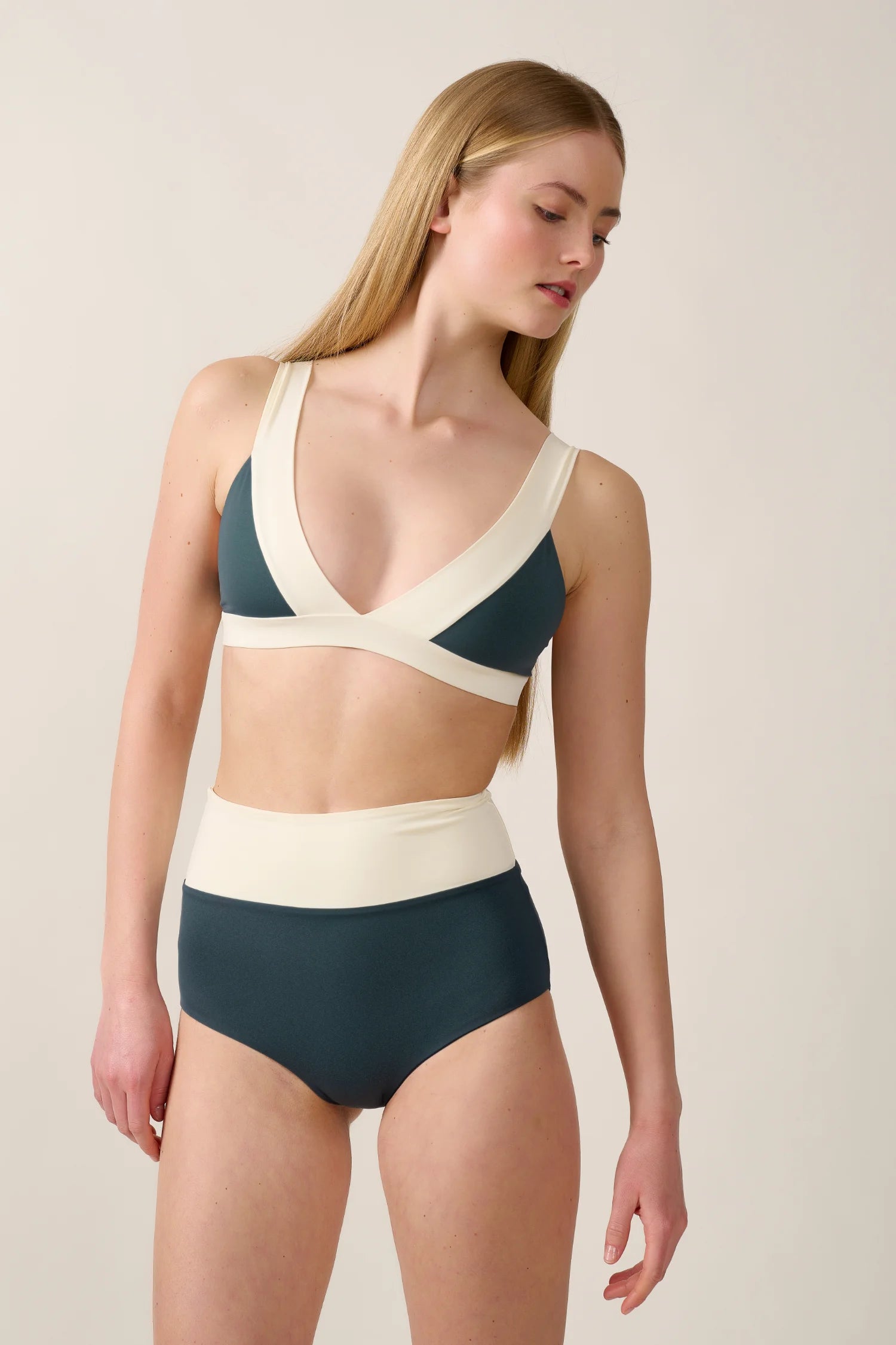 Frau trägt MYMARINI Bikinitop mit V-Ausschnitt und Bikinihose mit High Waist in Dunkelgrün und Creme.#color_black-grey-white