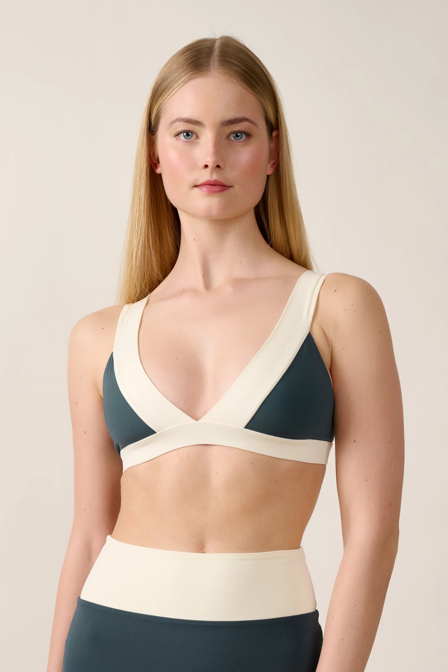 Frau trägt MYMARINI Bikinitop mit V-Ausschnitt und breiten Trägern in Dunkelgrün und Creme.#color_black-grey-white