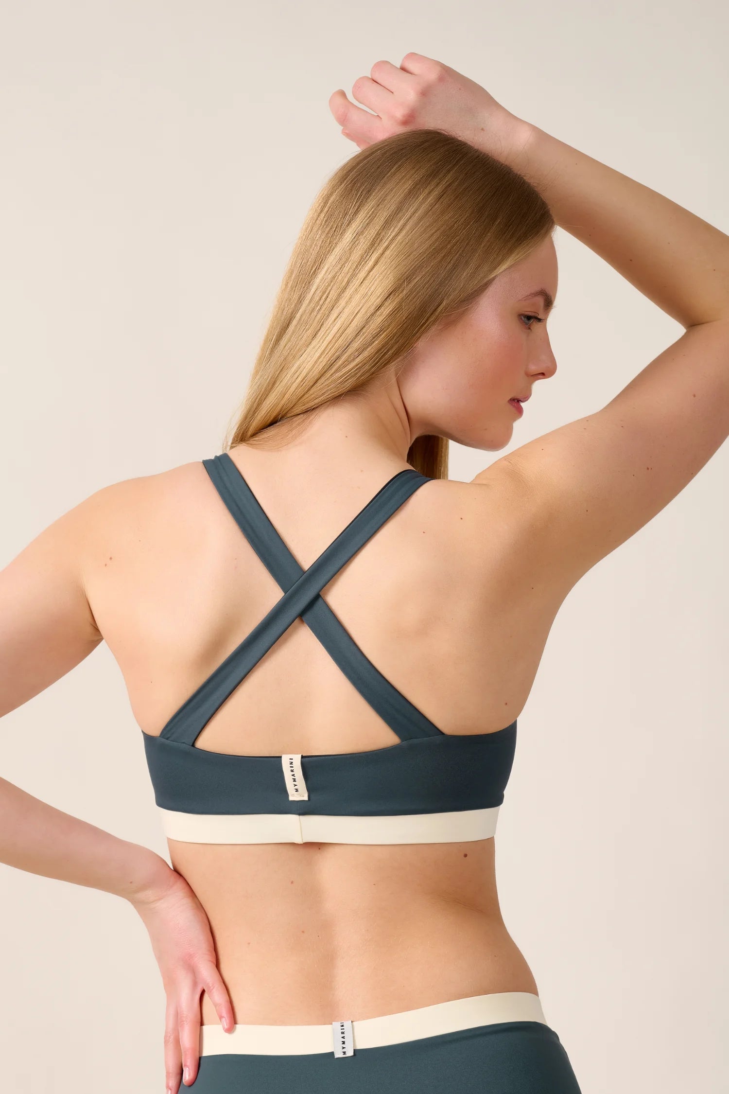 Frau trägt MYMARINI Bikinitop mit breiten, überkreuzten Trägern in Dunkelgrün.#color_black-grey-white