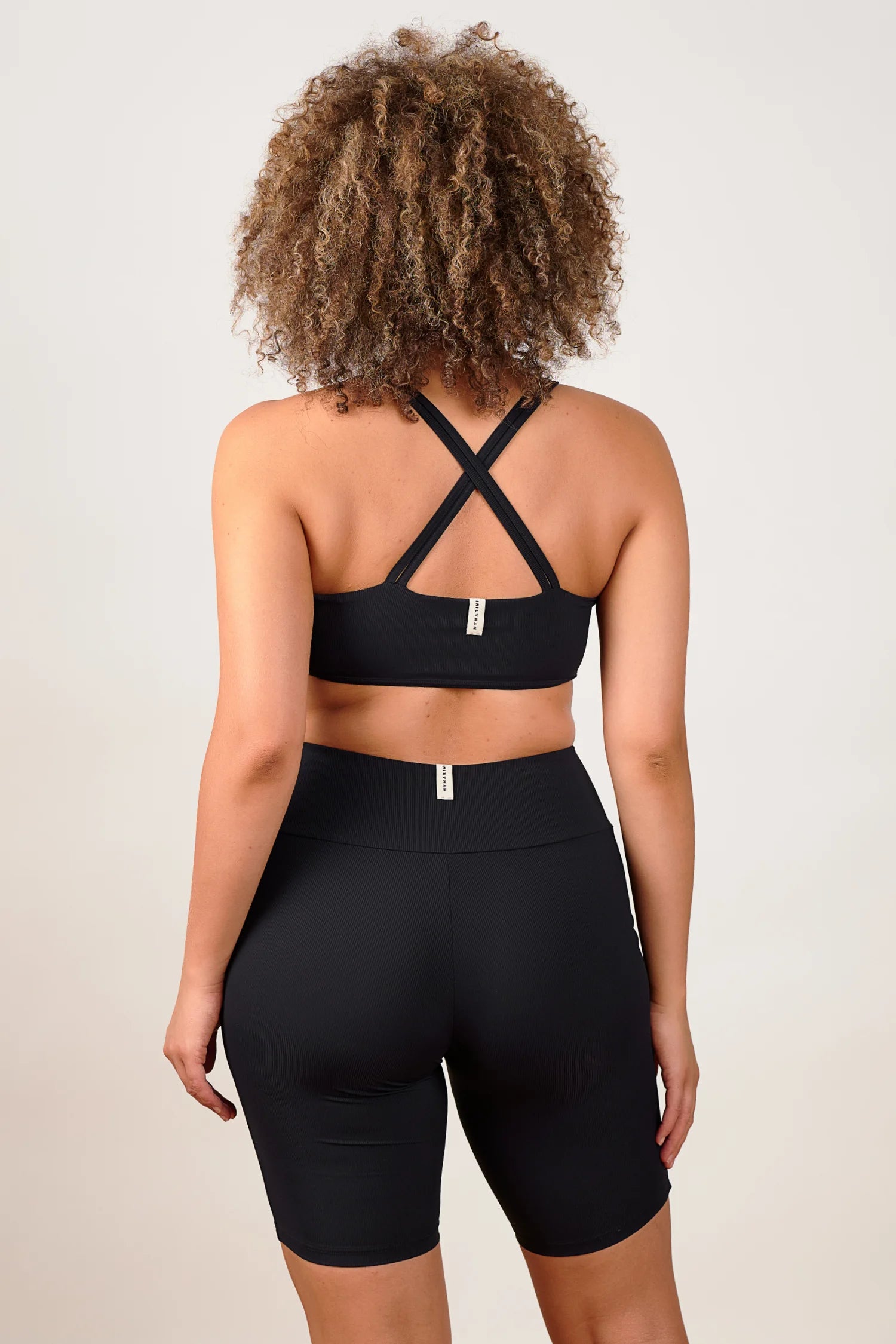 Person von hinten in schwarzem MYMARINI Cross Top und High Waist Shorts.#color_black