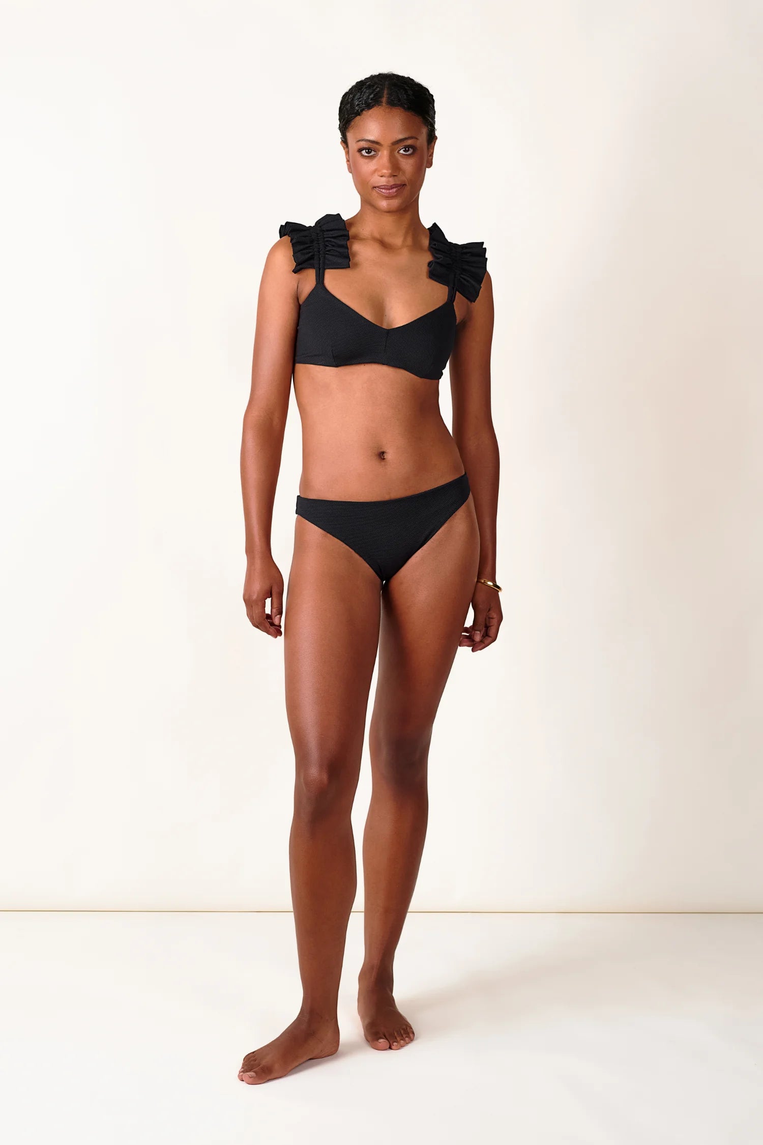 Frau trägt MYMARINI Bikini mit breiten Trägern und V-Ausschnitt in Schwarz.#color_black