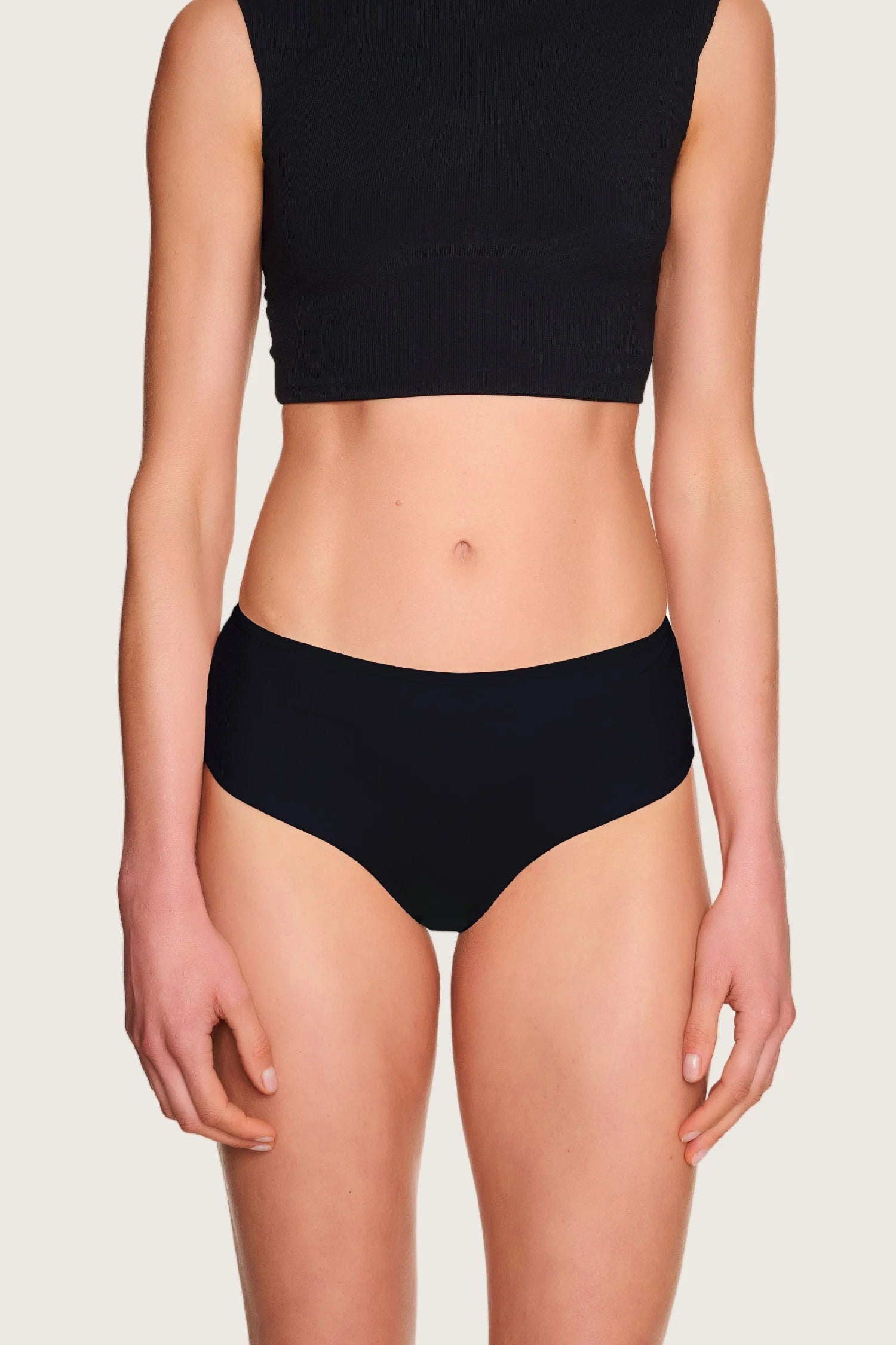 Person trägt schwarzes MYMARINI Bikinitop mit breiten Trägern und schwarze Bikinihose mit hohem Beinausschnitt.#color_black