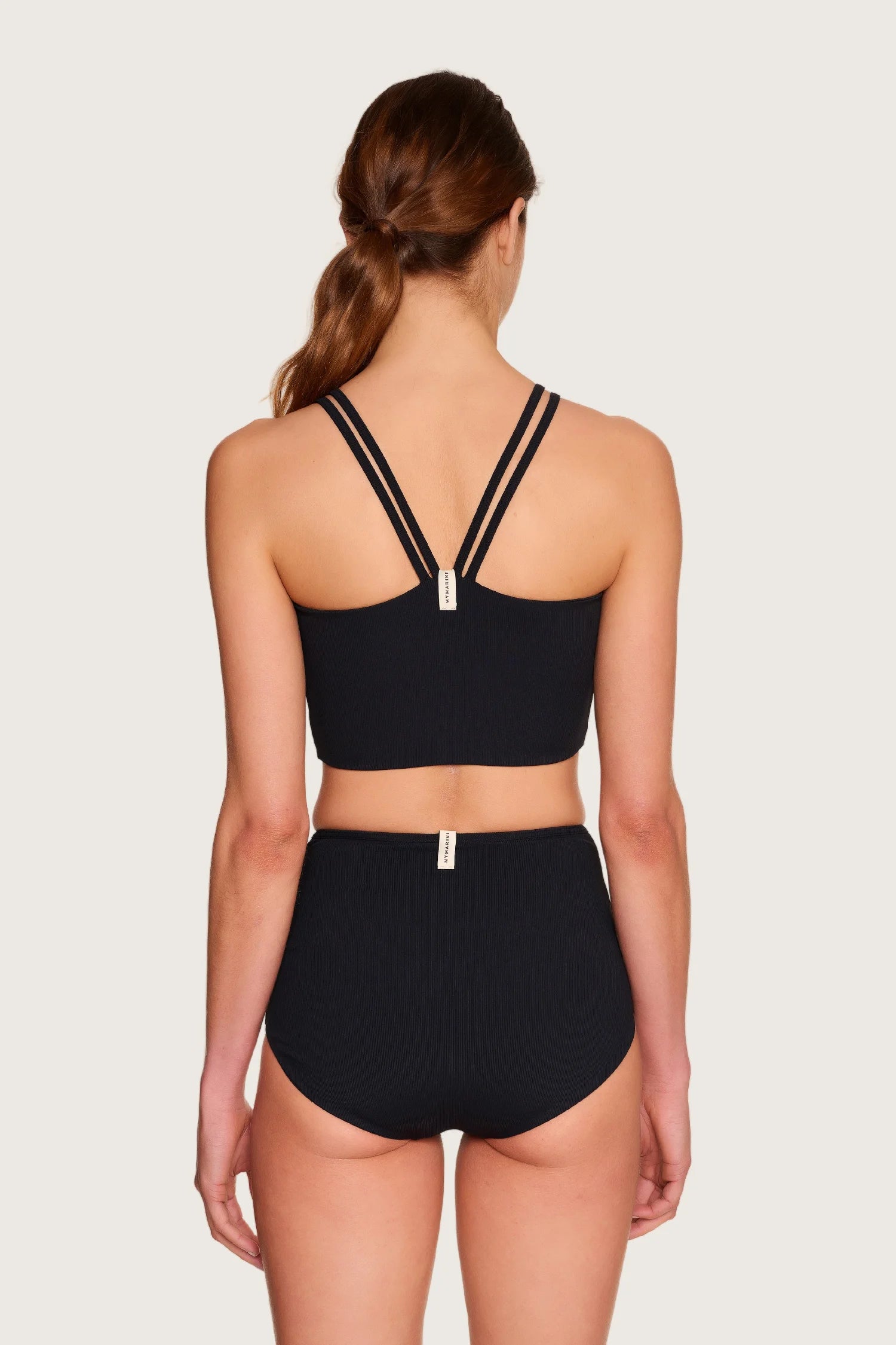Rückansicht einer Person in schwarzem MYMARINI-Bikini mit breiten Trägern und High-Waist-Schnitt.#color_black