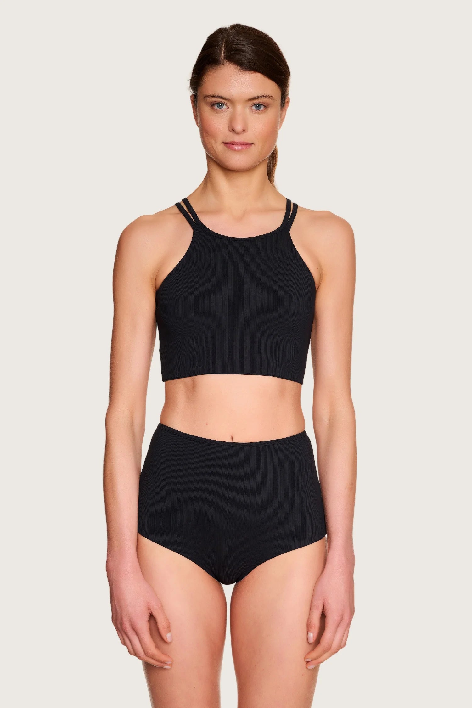 Person trägt MYMARINI Bikinihose mit hohem Bund und hochgeschlossenem Bikinitop in Schwarz.#color_black