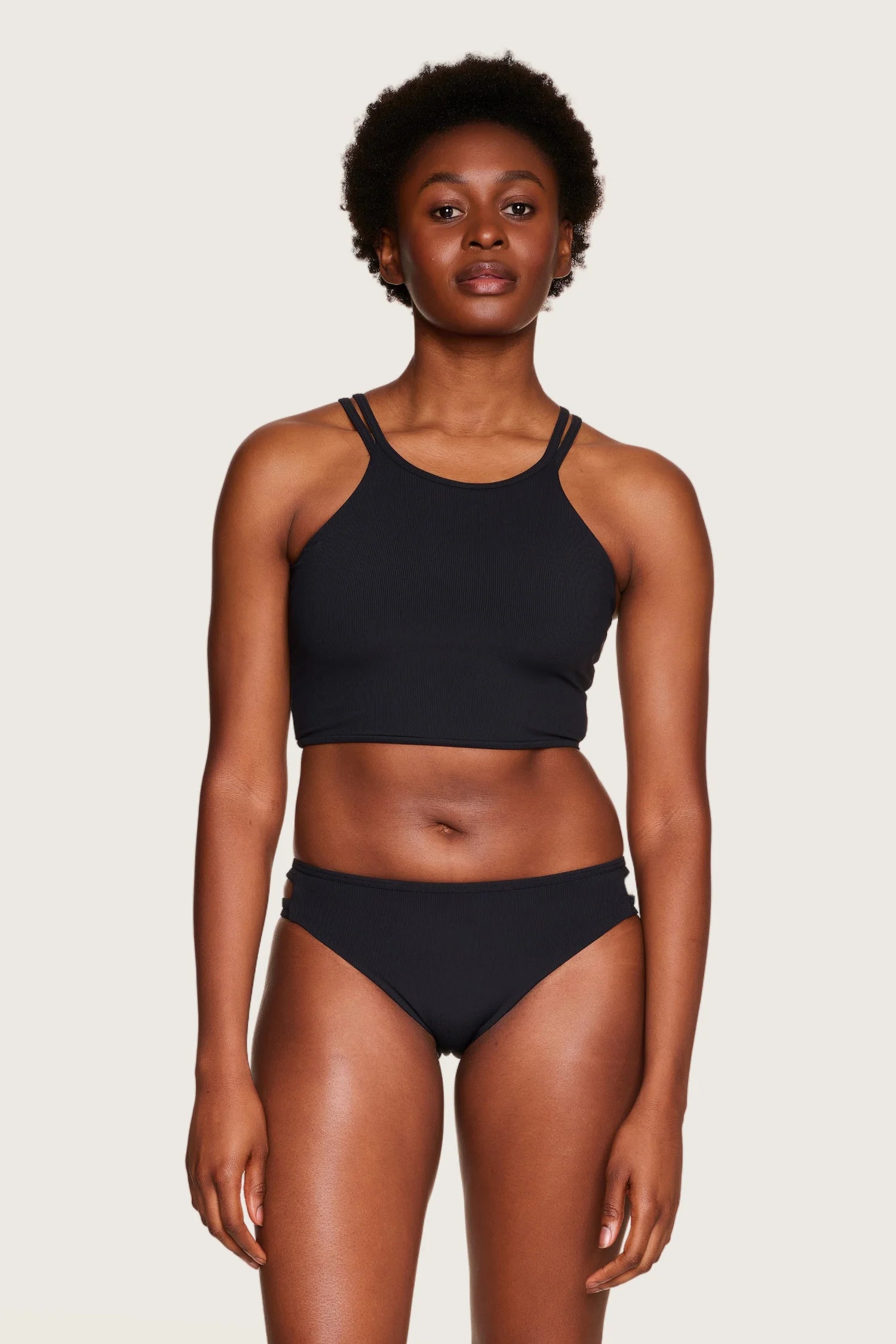 Person trägt schwarzen MYMARINI Bikini mit hochgeschlossenem Top und Bikinihose in Mid rise.#color_black