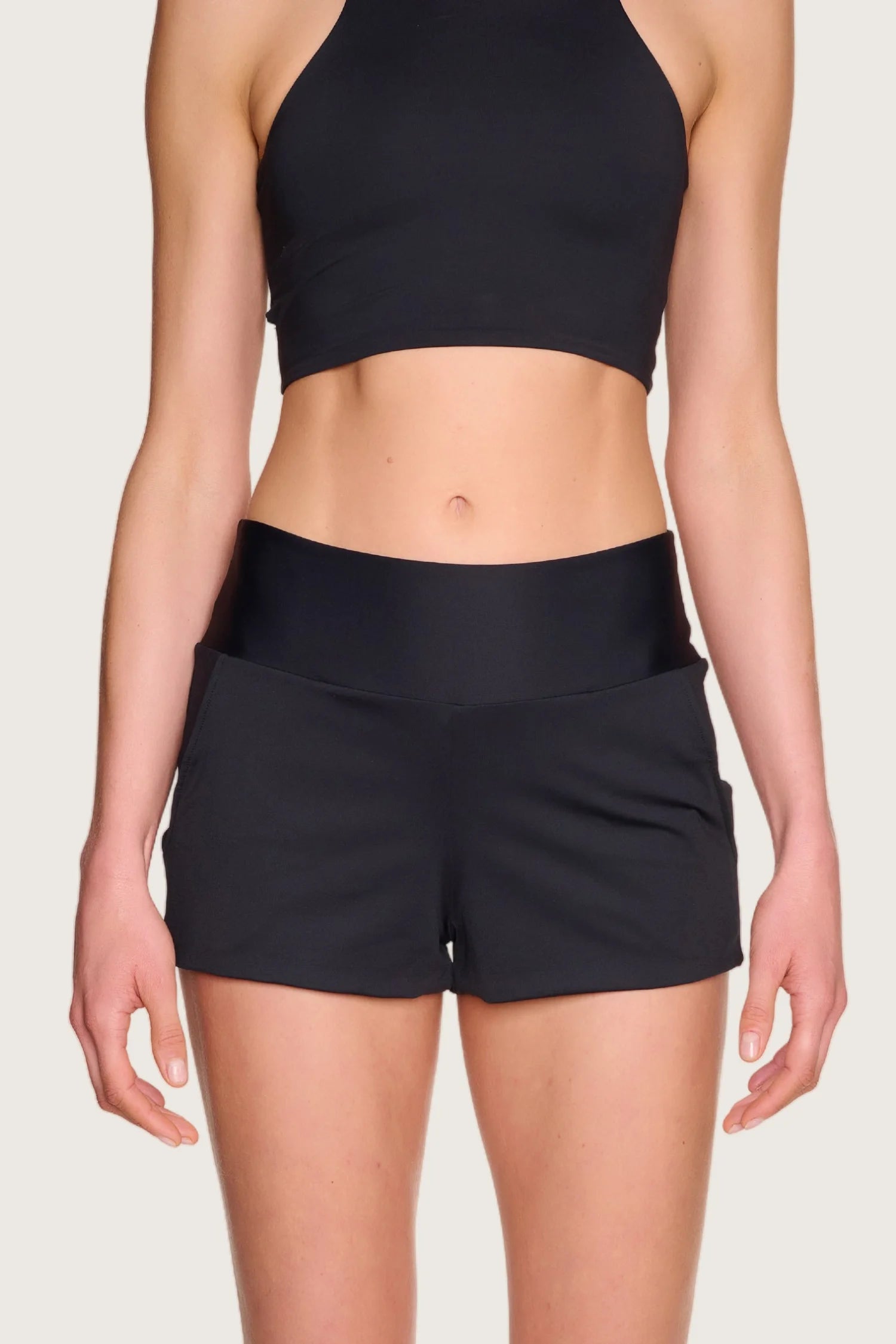 Person trägt MYMARINI Bikinitop mit hohem Ausschnitt und Shorts in Schwarz.#color_black