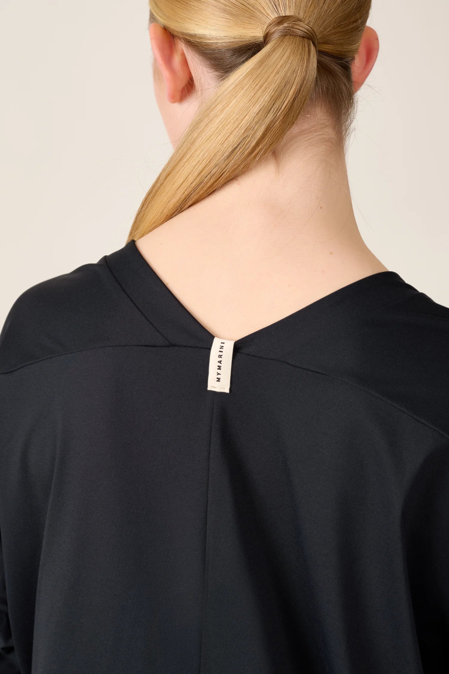 Person von hinten in schwarzem MYMARINI-Shirt mit V-Ausschnitt, Etikett sichtbar im Nackenbereich.#color_black