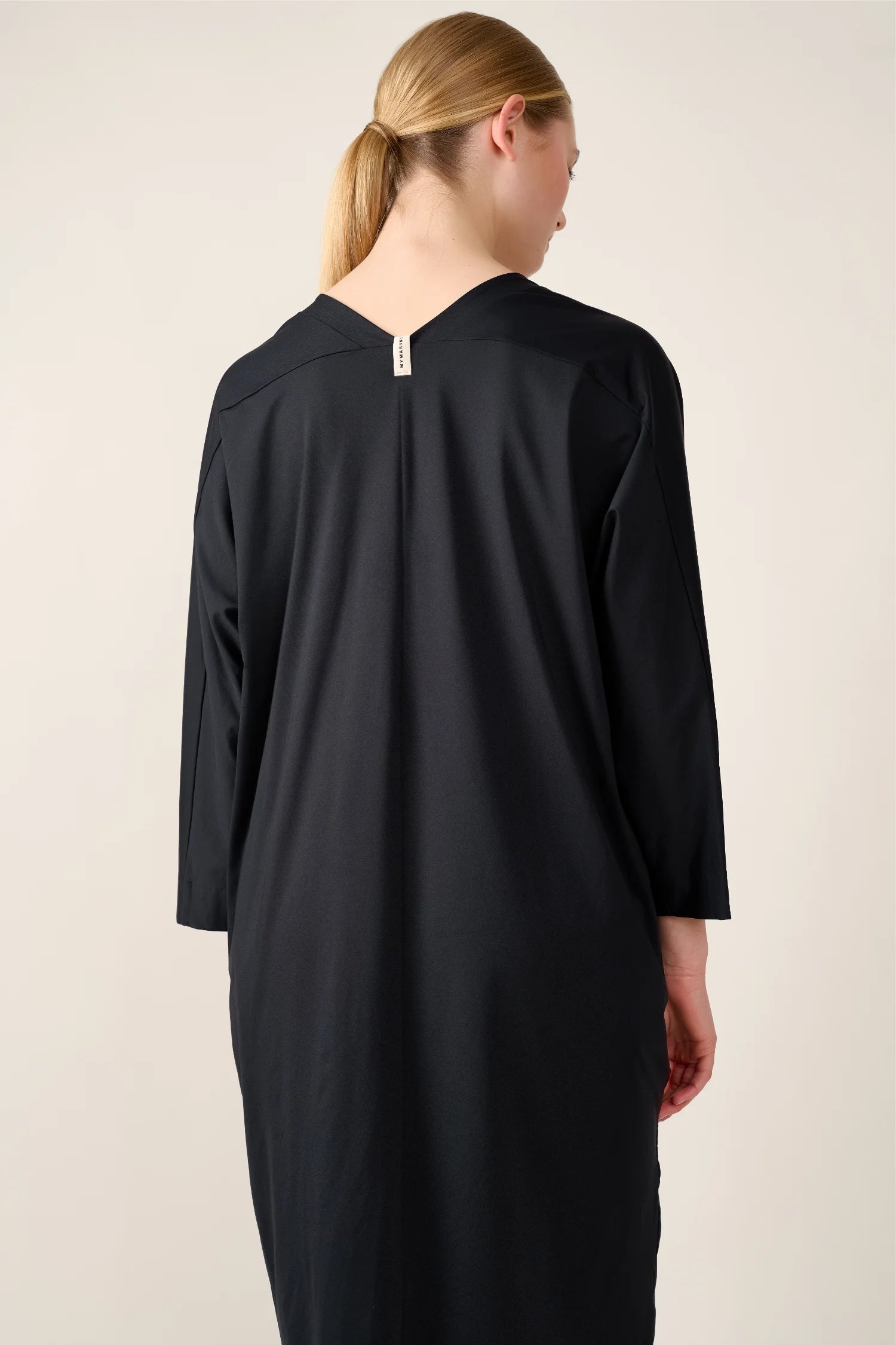 Person von hinten in einem schwarzen MYMARINI-Kleid mit V-Ausschnitt und Dreiviertelärmeln.#color_black