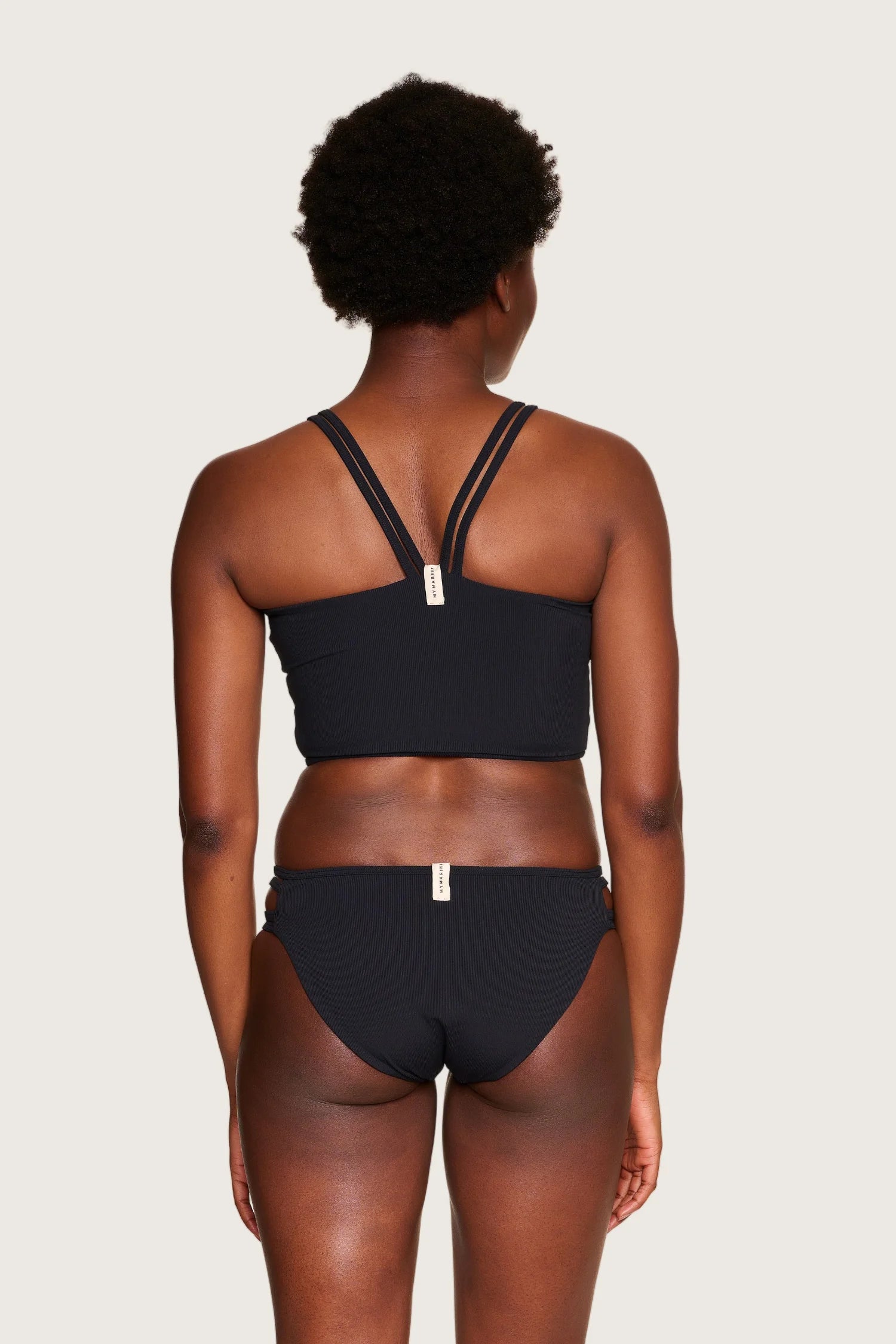 Rückansicht eines schwarzen MYMARINI Bikinitops mit breiten Trägern und einer Bikinihose mit hohem Beinausschnitt.#color_black