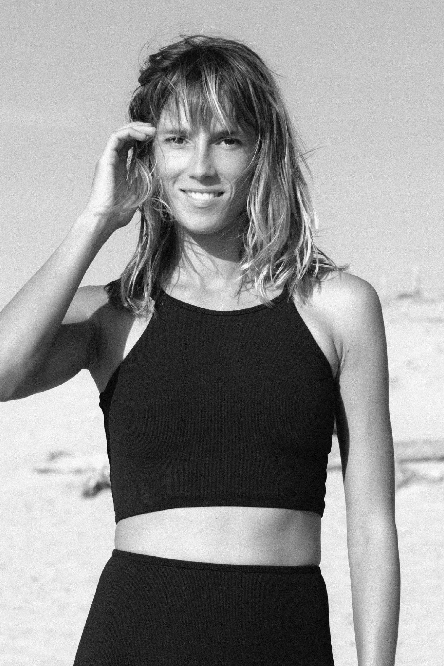 Frau am Strand trägt ein schwarzes MYMARINI Bikinitop mit breiten Trägern und hoch geschlossenem Schnitt.#color_black