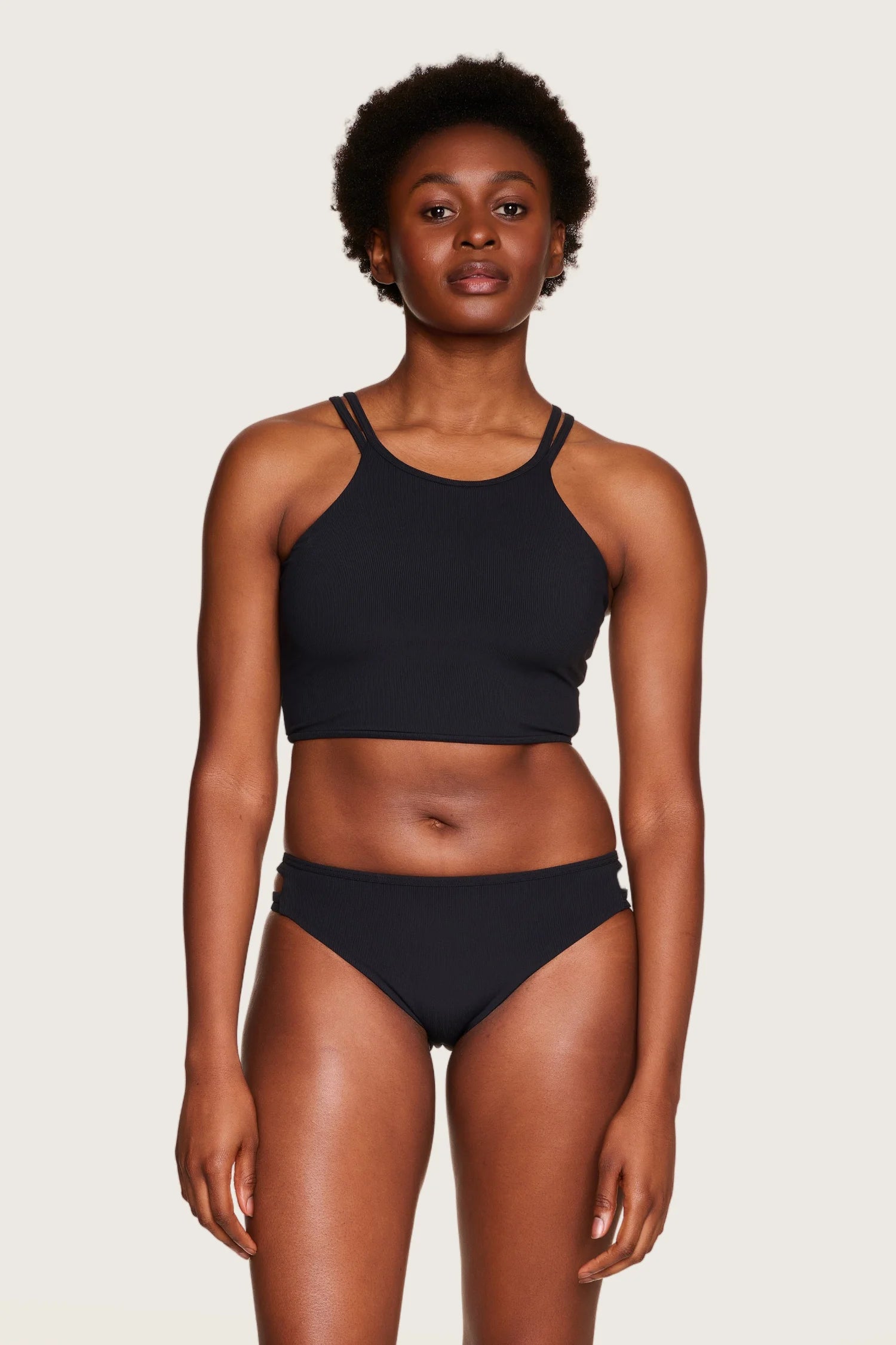 Frau trägt schwarzes MYMARINI Bikinitop mit hohem Ausschnitt und schmalen Trägern.#color_black