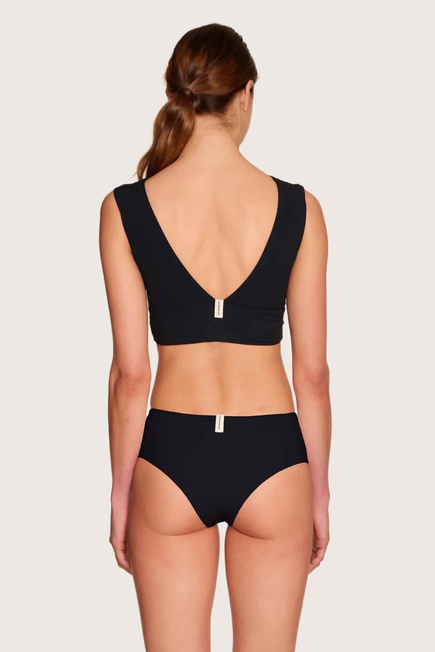 Frau in MYMARINI Bikinitop mit tiefem Rückenausschnitt und breiten Trägern, dazu passende Bikinihose.#color_black