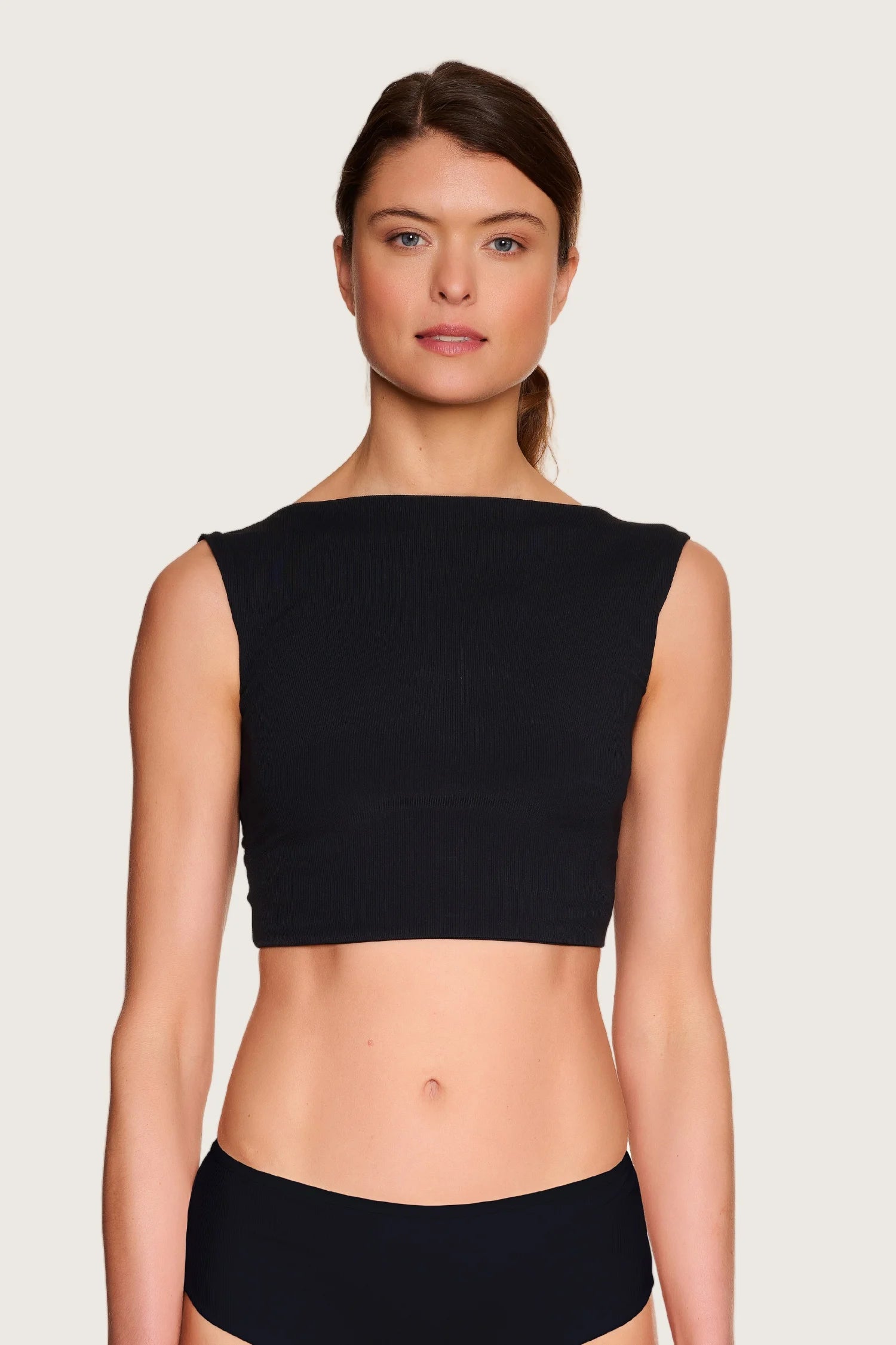 Frau trägt schwarzes MYMARINI Bikinitop mit breiten Trägern und hoch geschlossenem Schnitt.#color_black