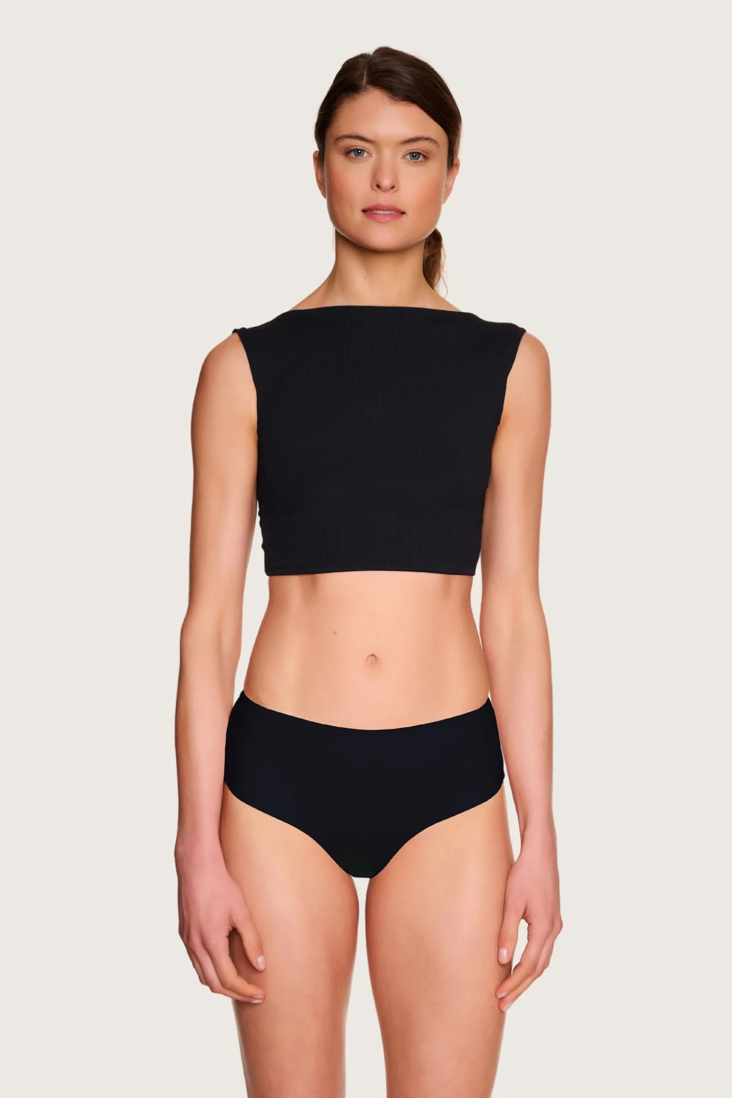 Frau trägt schwarzes MYMARINI Bikinitop mit breiten Trägern und hoch geschlossenem Schnitt.#color_black