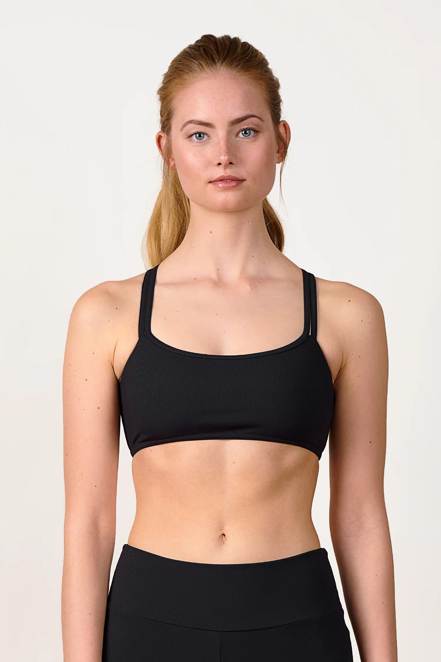 Frau trägt MYMARINI Bikinitop mit breiten Trägern in Schwarz, hoch geschlossen.#color_black