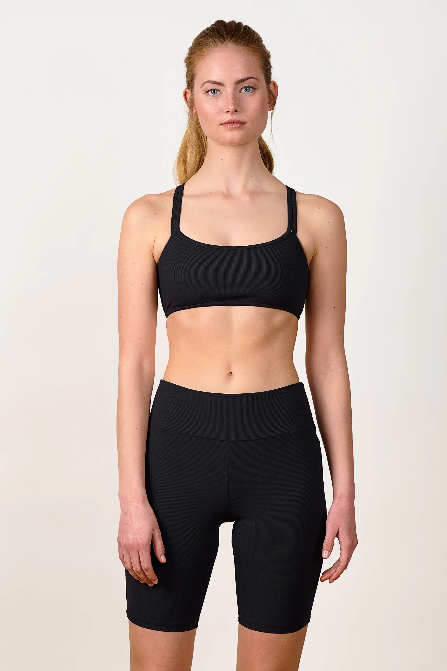 Frau trägt MYMARINI Bikinitop mit breiten Trägern in Schwarz, hoch geschlossen.#color_black