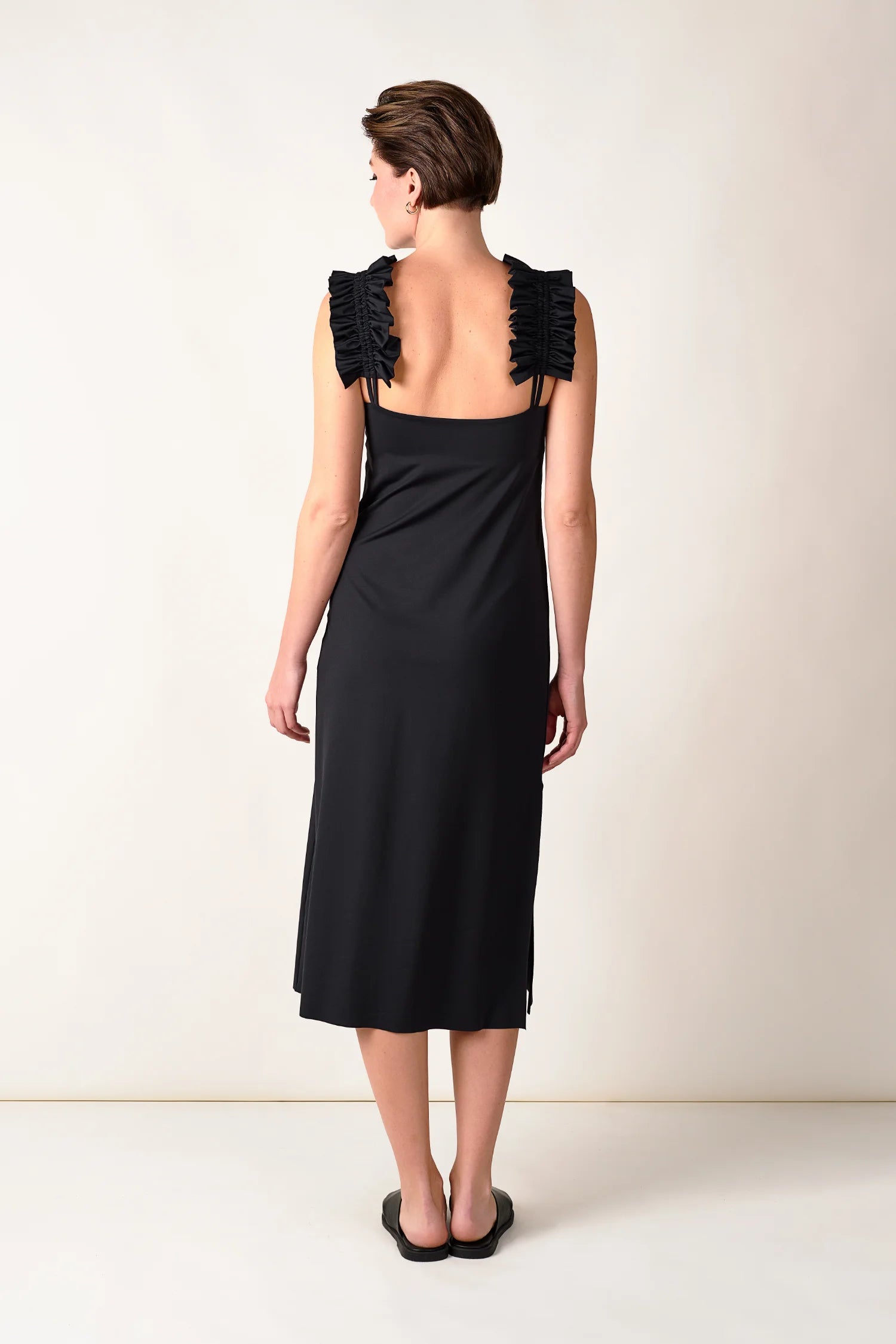 Rückenansicht eines schwarzen MYMARINI Kleides mit breiten Trägern und tiefem Rückenausschnitt.#color_black