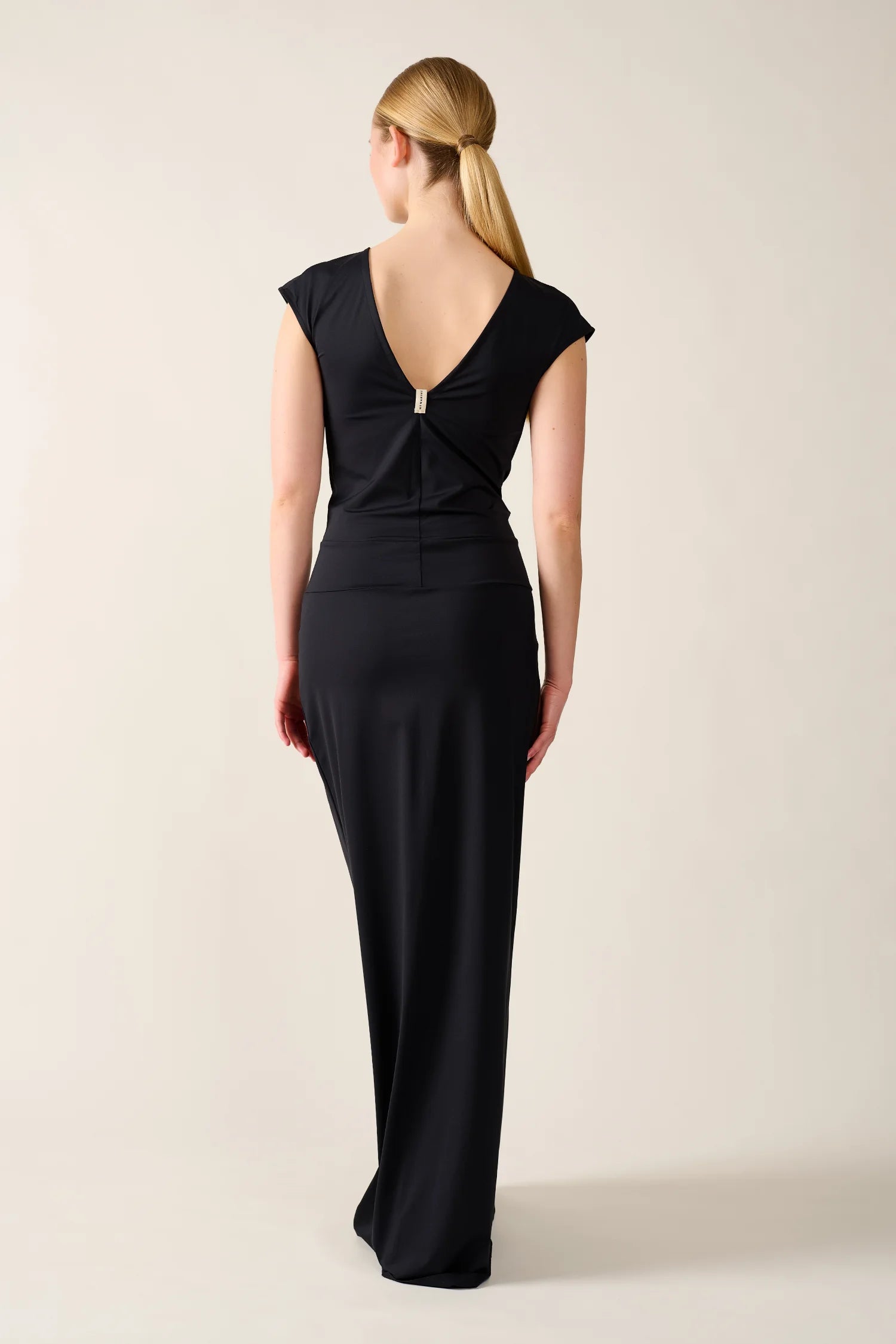 Person trägt ein schwarzes MYMARINI-Kleid mit tiefem Rückenausschnitt.#color_black