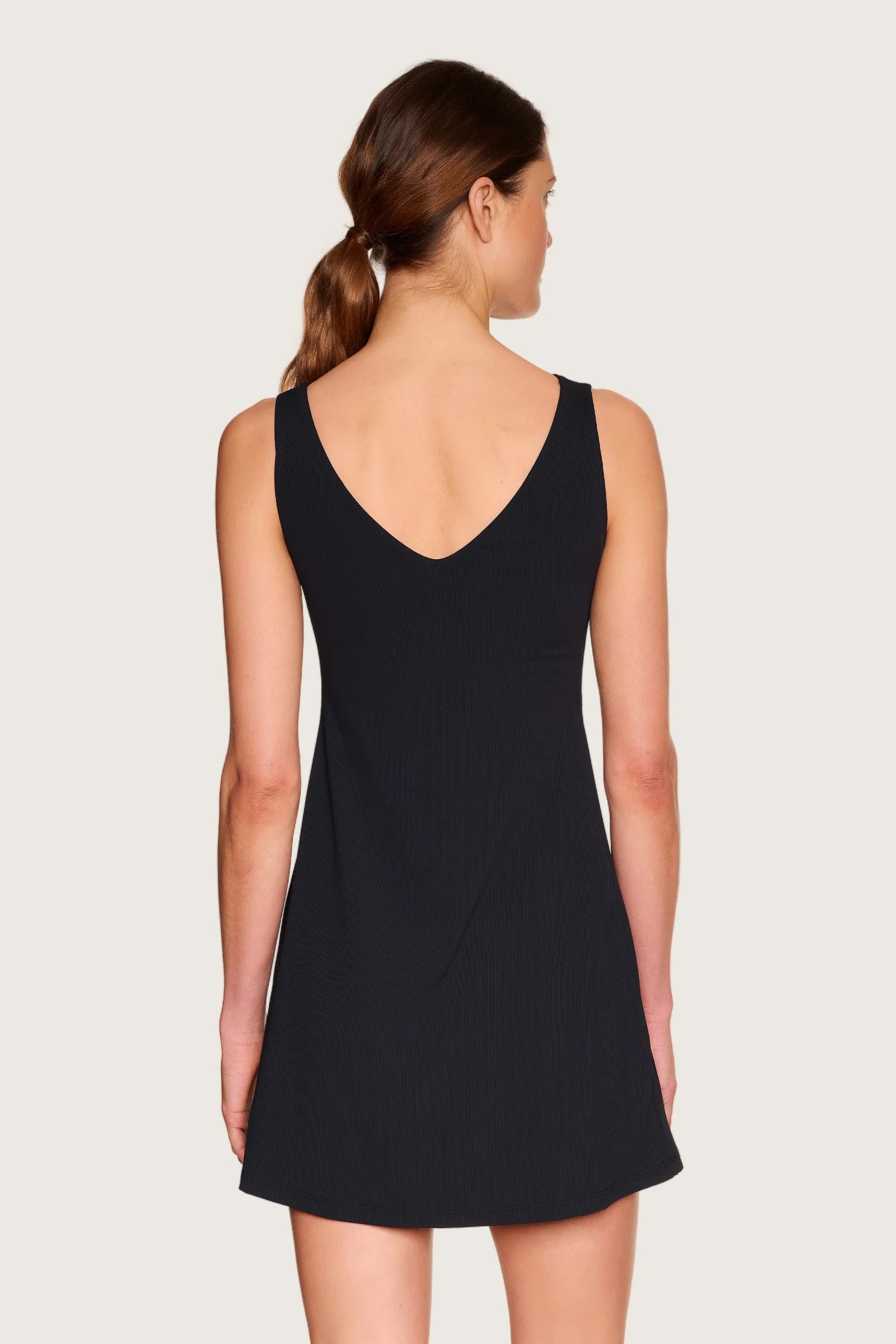 Frau von hinten in schwarzem MYMARINI-Kleid mit V-Ausschnitt.#color_black