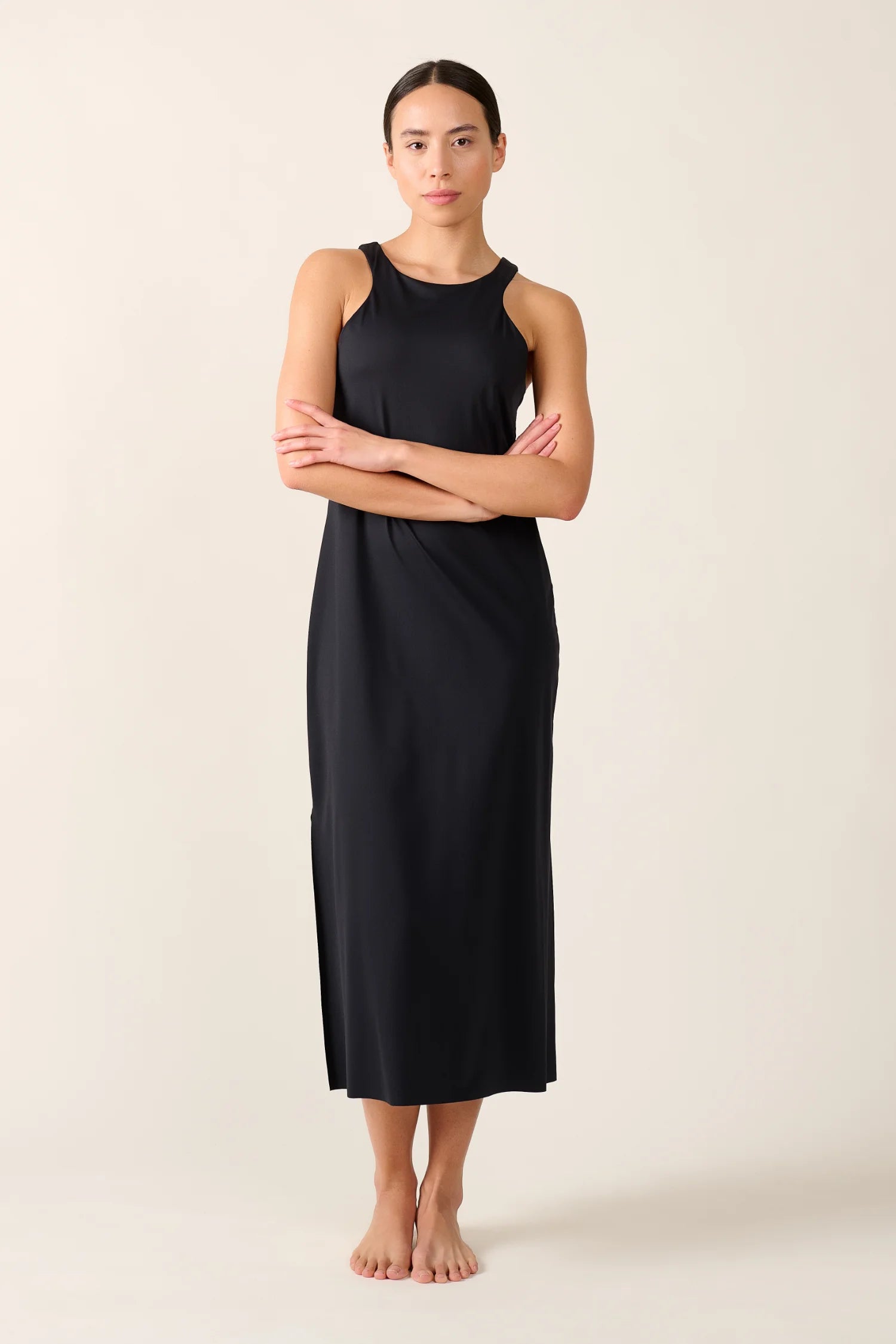 Frau trägt schwarzes MYMARINI-Kleid mit breiten Trägern, stehend vor neutralem Hintergrund.#color_black