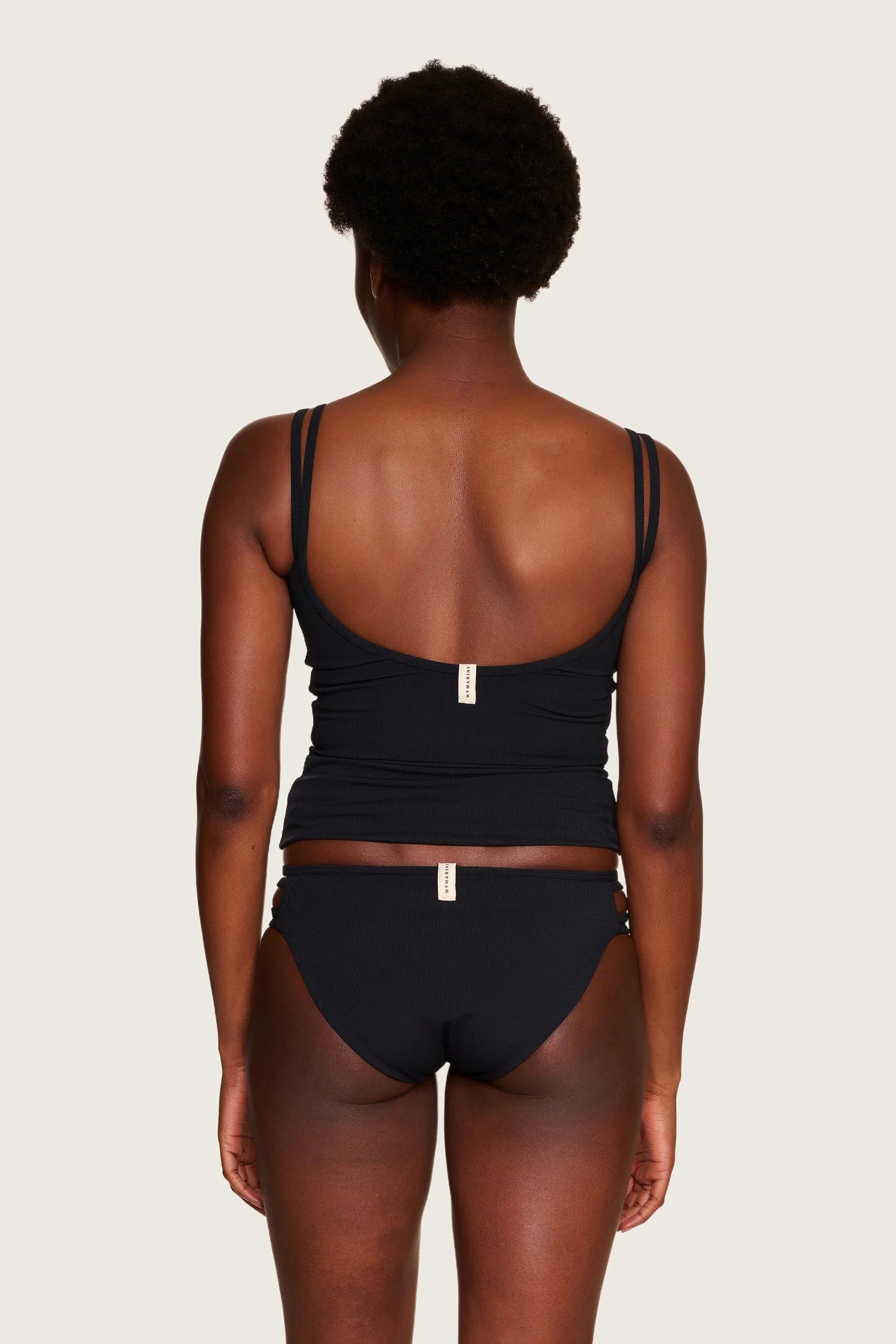 Person von hinten in schwarzem MYMARINI-Bikinitop mit tiefem Rückenausschnitt und Spaghettiträgern.#color_black