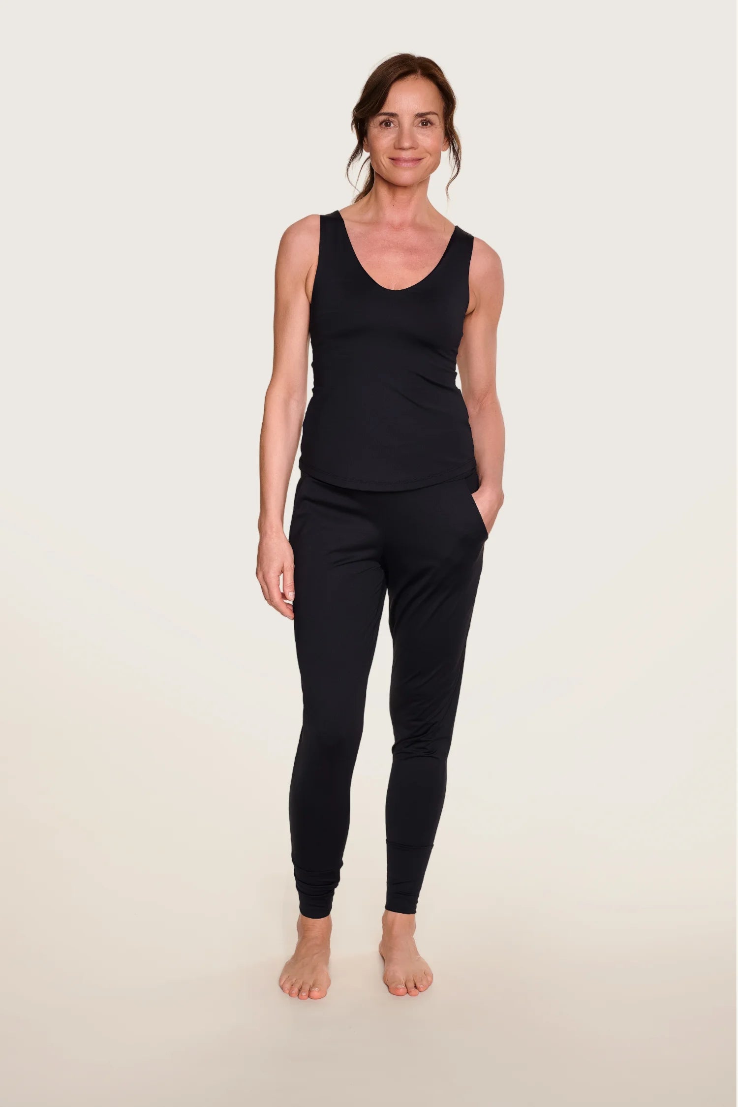 Frau trägt schwarzes MYMARINI-Top mit Rundhalsausschnitt und passende Hose, stehend vor hellem Hintergrund.#color_black