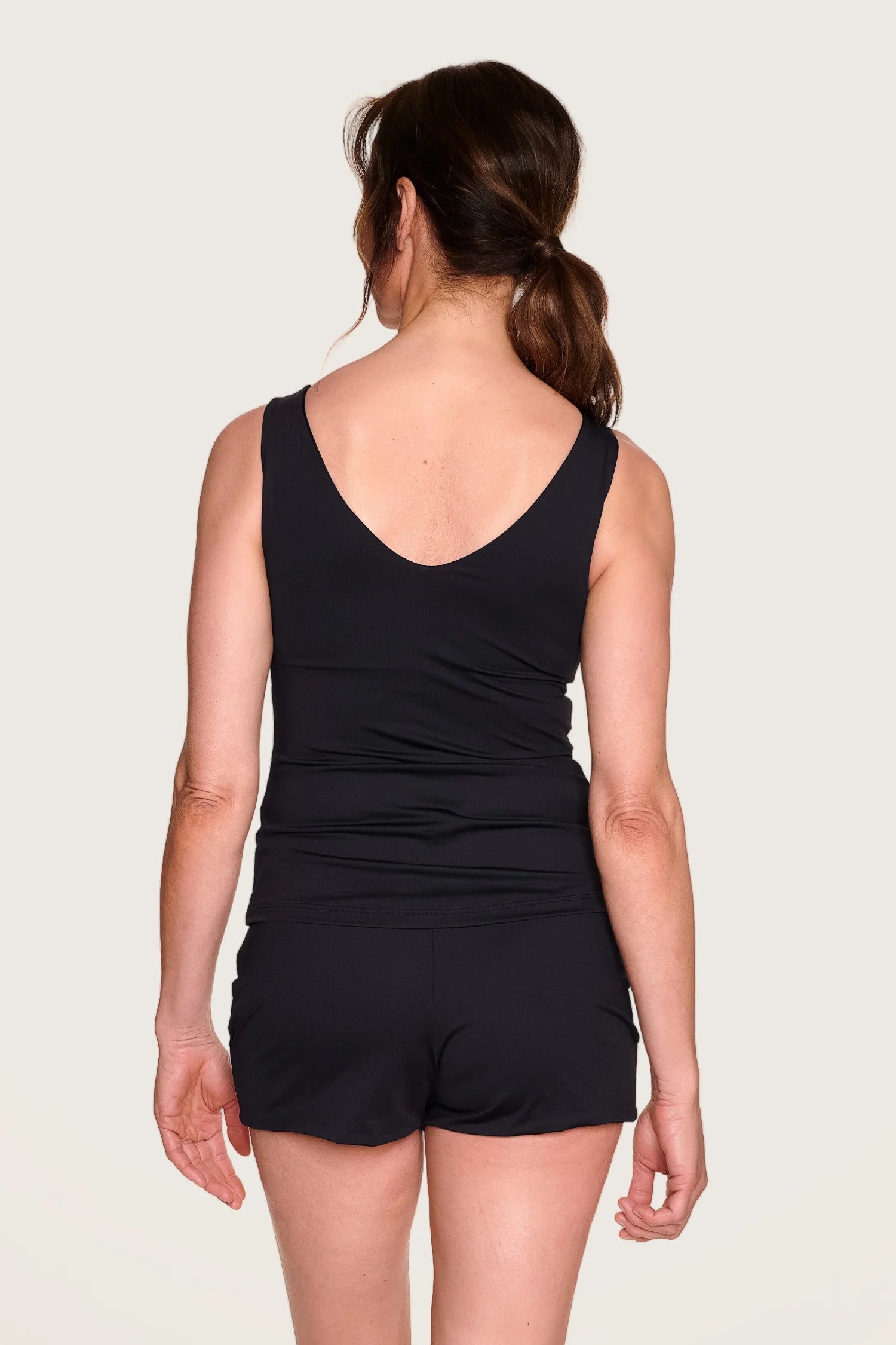 Frau in schwarzem MYMARINI-Top mit V-Ausschnitt und Shorts, von hinten fotografiert.#color_black