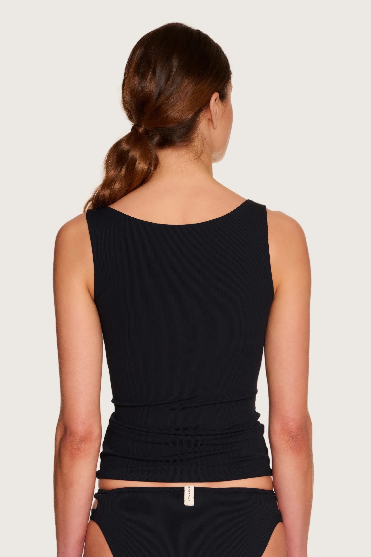 Rückansicht einer Frau in schwarzem MYMARINI-Top mit breiten Trägern und Bikinihose mit hohem Beinausschnitt.#color_black