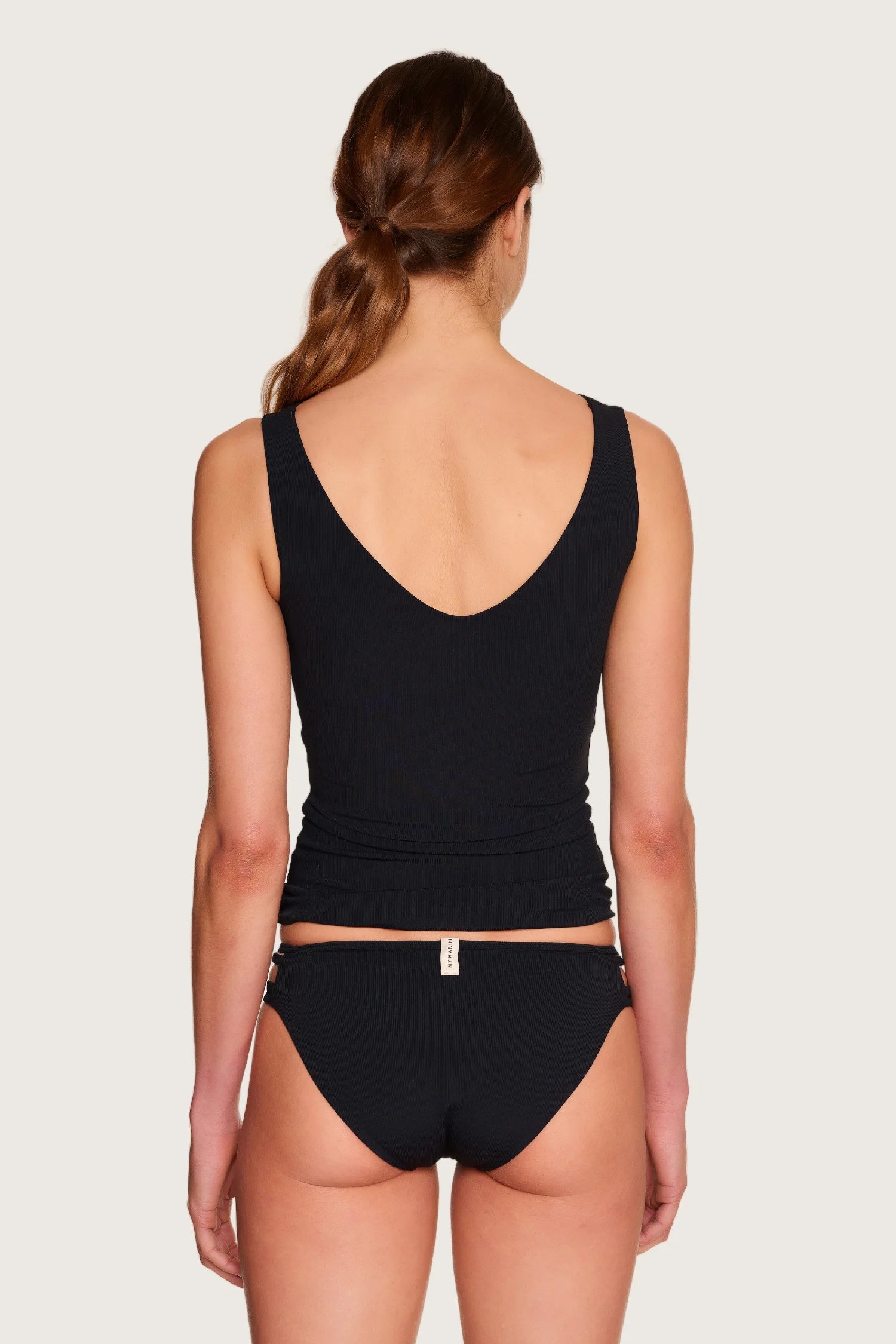 Frau in schwarzem MYMARINI-Bikinitop mit V-Ausschnitt und passender Bikinihose, Rückansicht.#color_black