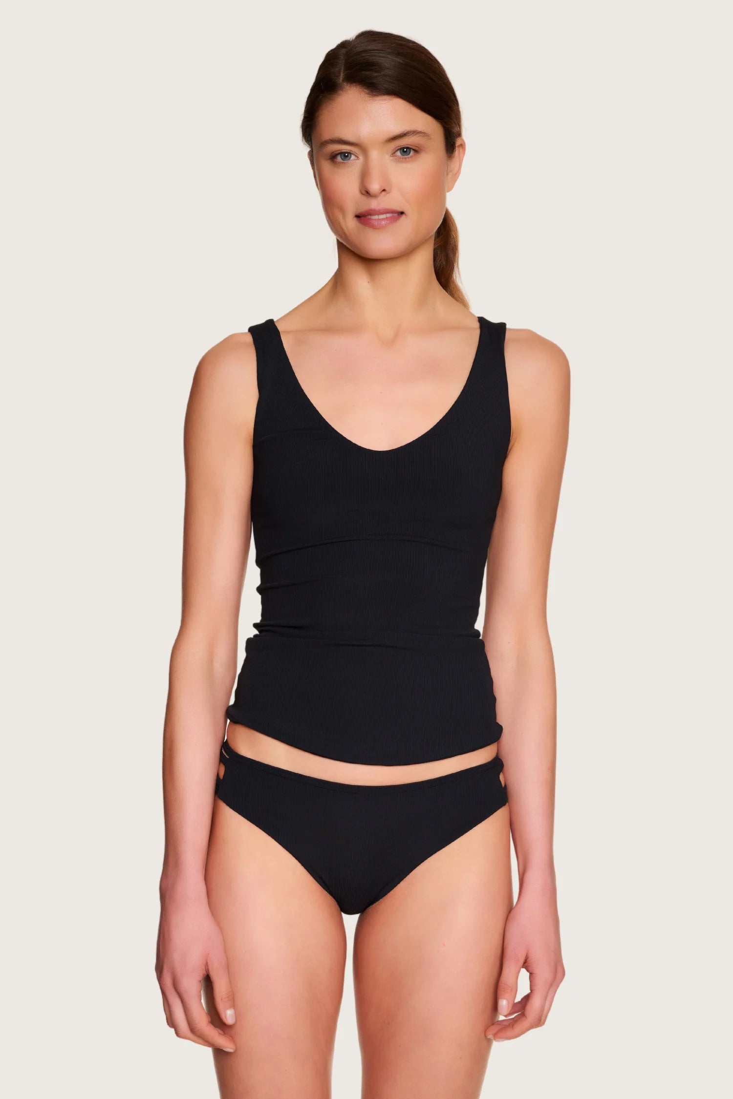 Frau trägt schwarzes MYMARINI Bikinitop mit V-Ausschnitt und breite Träger, kombiniert mit passender Bikinihose.#color_black