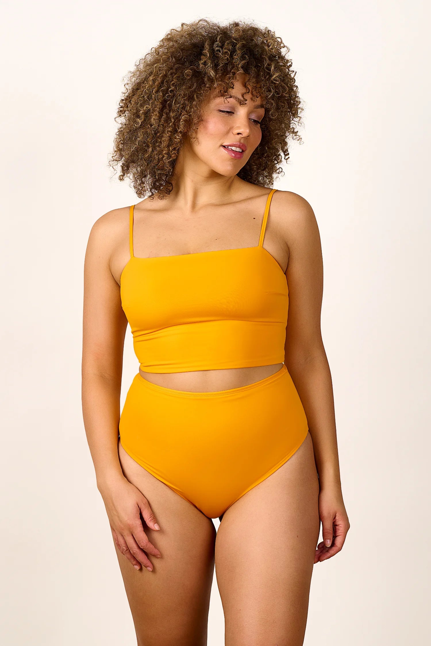 Frau trägt MYMARINI Bikini mit Spaghettiträgern und High-Waist-Schnitt in leuchtendem Gelb.#color_buttermilk-soleil