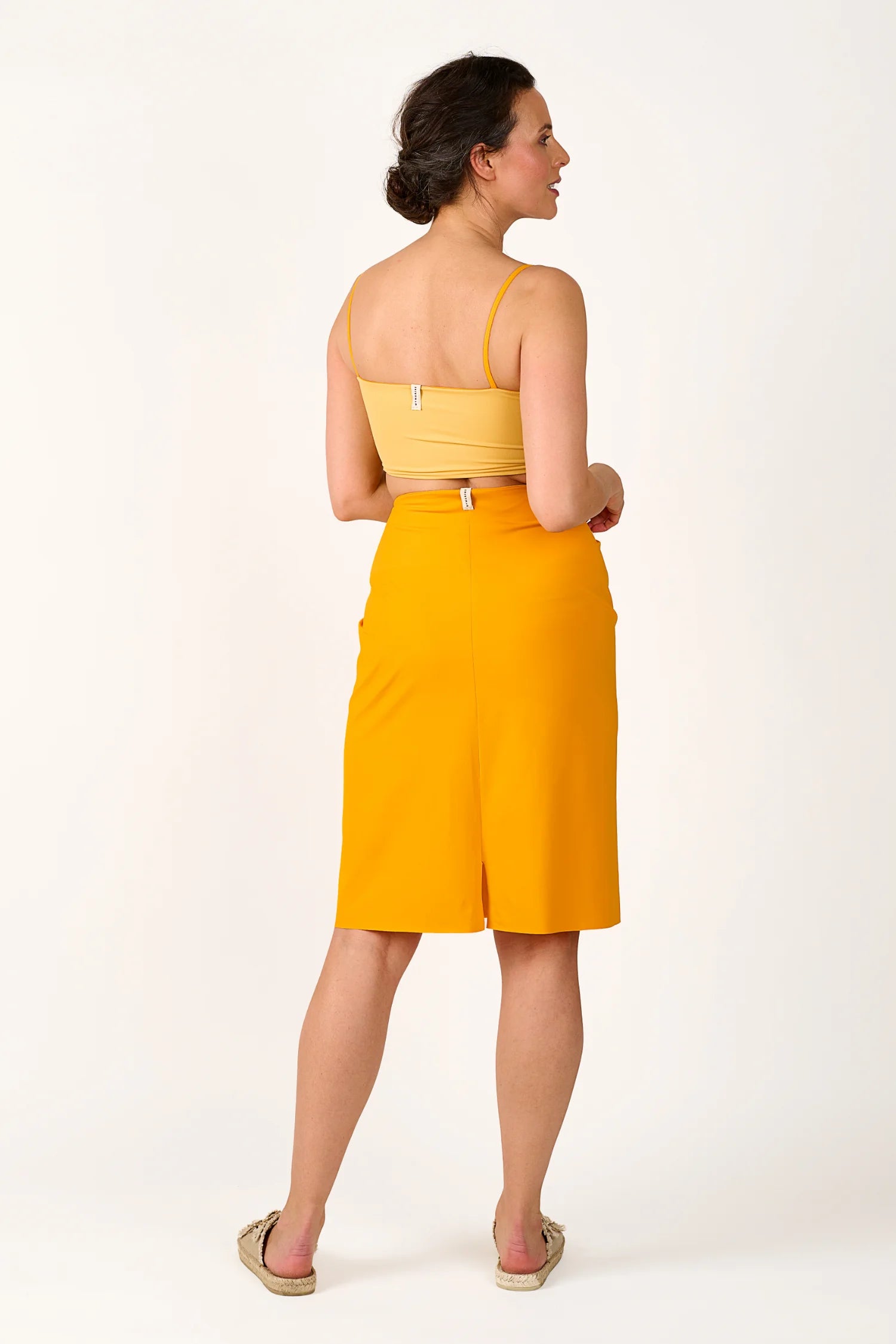 Frau in gelbem MYMARINI Top mit Spaghettiträgern und passendem Rock, von hinten gezeigt.#color_buttermilk-soleil