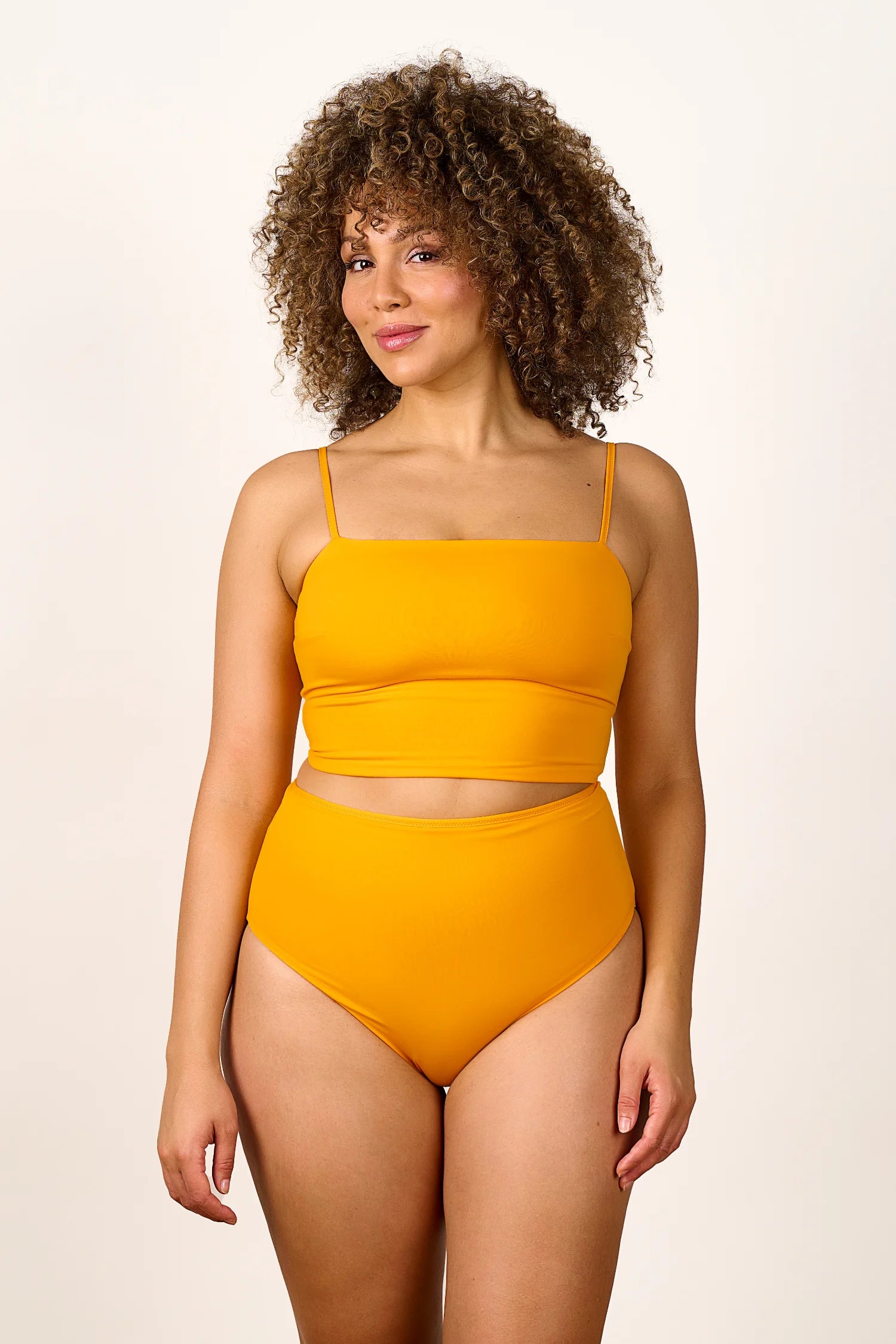 Frau trägt MYMARINI Bikinitop mit Spaghettiträgern und Bikinihose in High Waist, beide in leuchtendem Gelb.#color_buttermilk-soleil