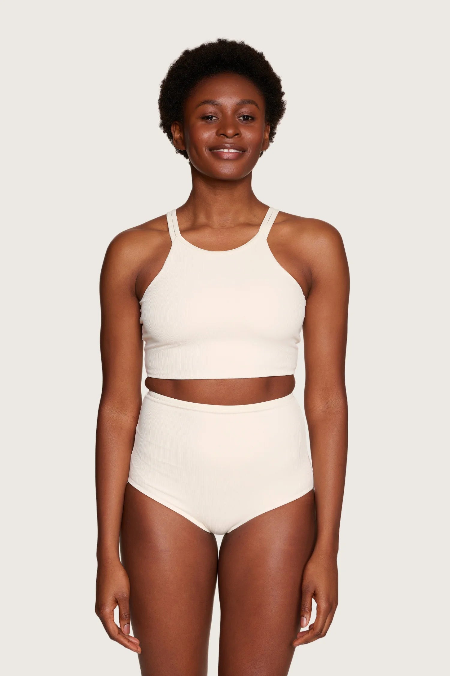 Person trägt MYMARINI Bikinitop mit breiten Trägern und hoch geschnittene Bikinihose in Creme.#color_off-white