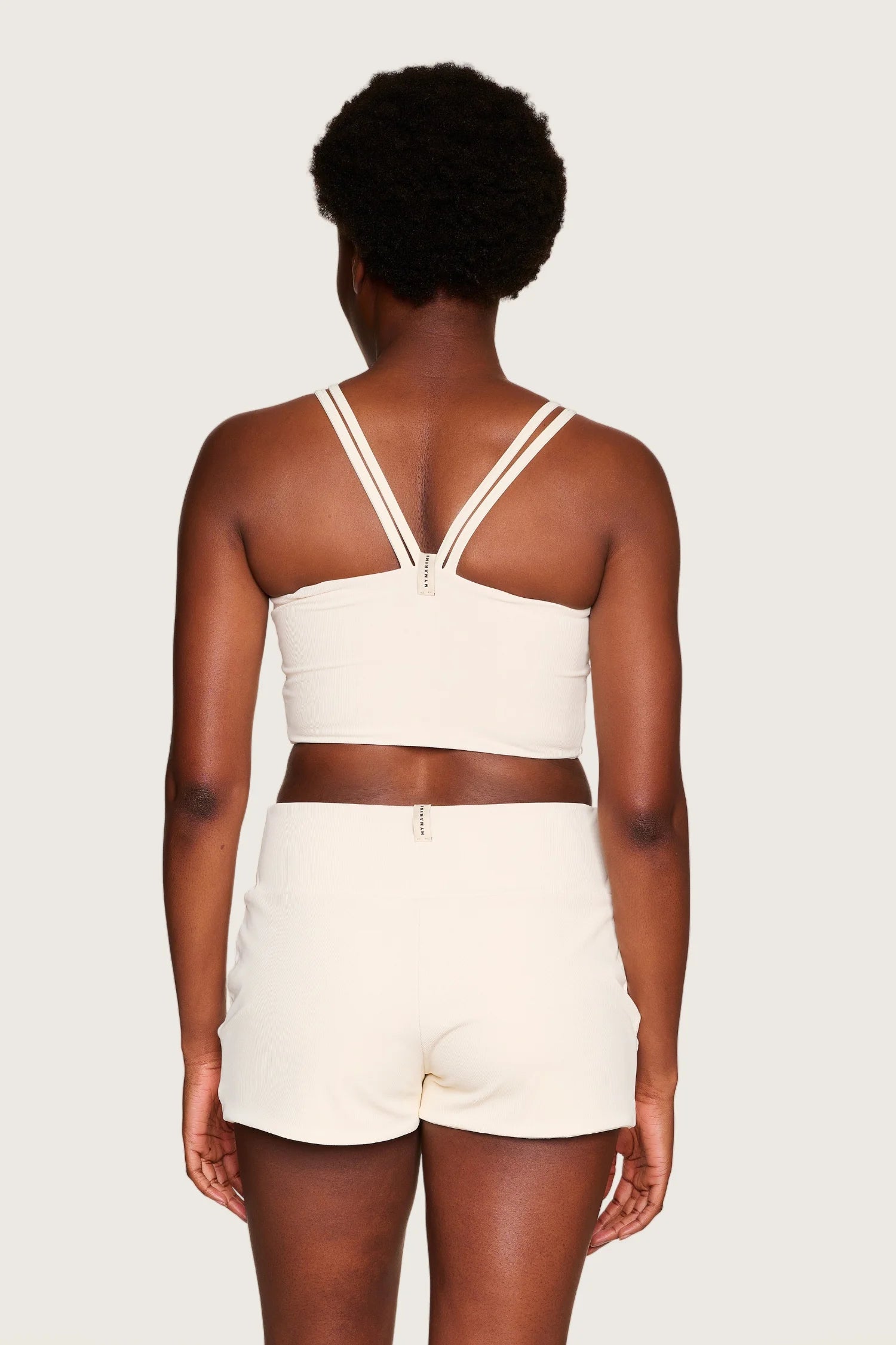 Rückansicht einer Person in MYMARINI Bikinitop mit breiten Trägern und Shorts in Cremeweiß.#color_off-white