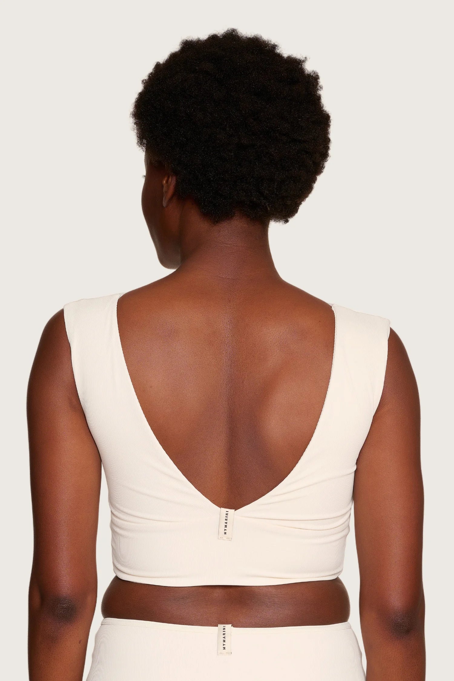 Rückansicht eines MYMARINI Bikinitops mit tiefem Rückenausschnitt und breiten Trägern in Cremeweiß.#color_off-white