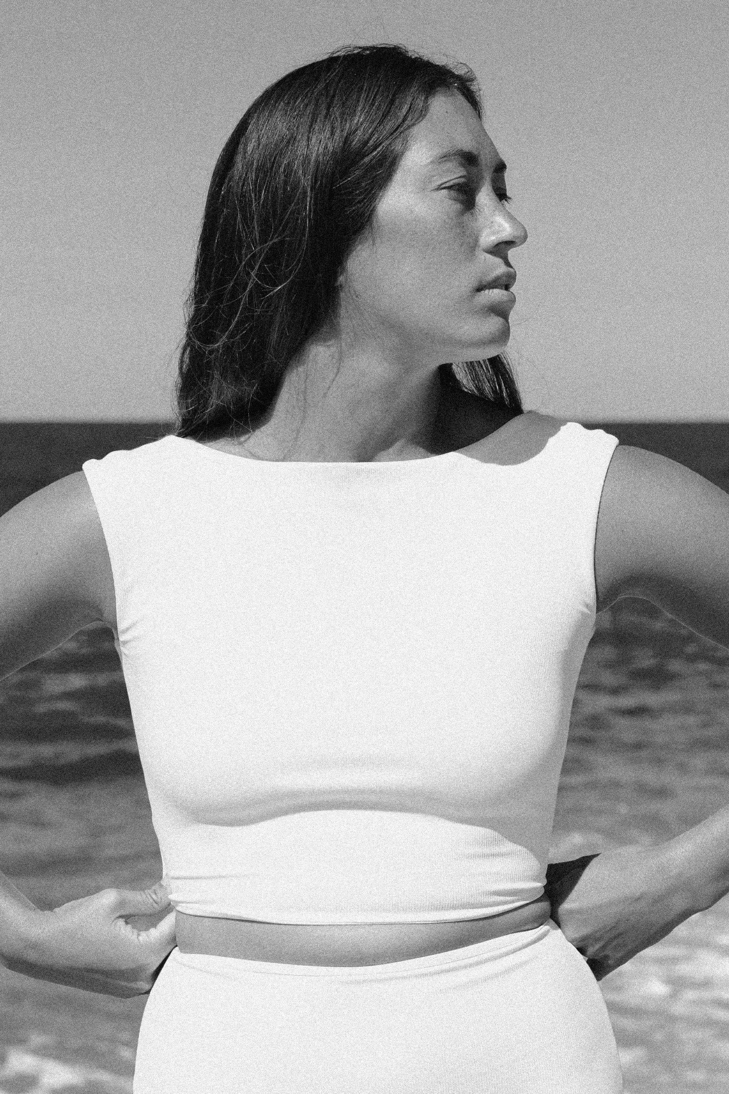 Frau am Strand trägt MYMARINI Top mit breiten Trägern und hohem Ausschnitt.#color_white