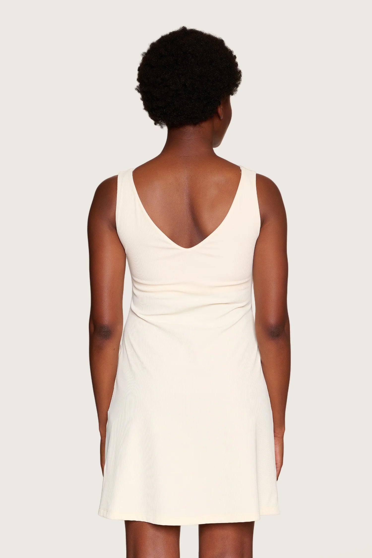 Person in cremefarbenem MYMARINI-Kleid mit V-Ausschnitt und breiten Trägern, von hinten gesehen.#color_off-white