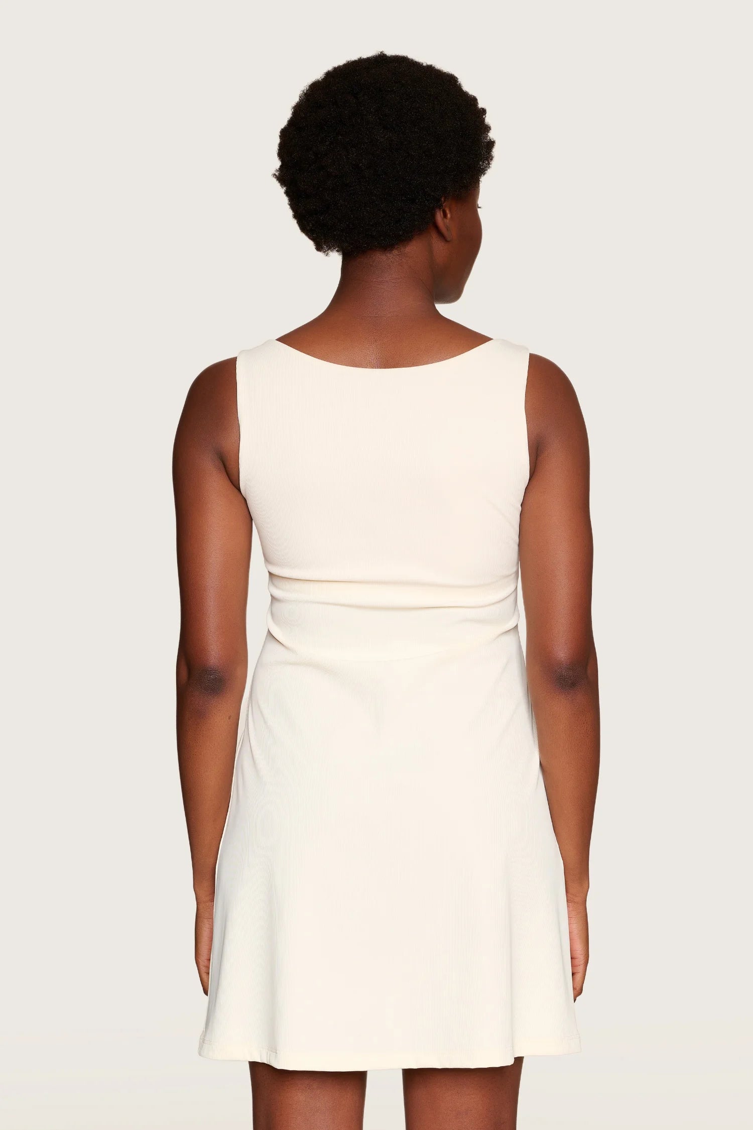 Person in cremefarbenem MYMARINI-Kleid mit breiten Trägern, von hinten gezeigt.#color_off-white